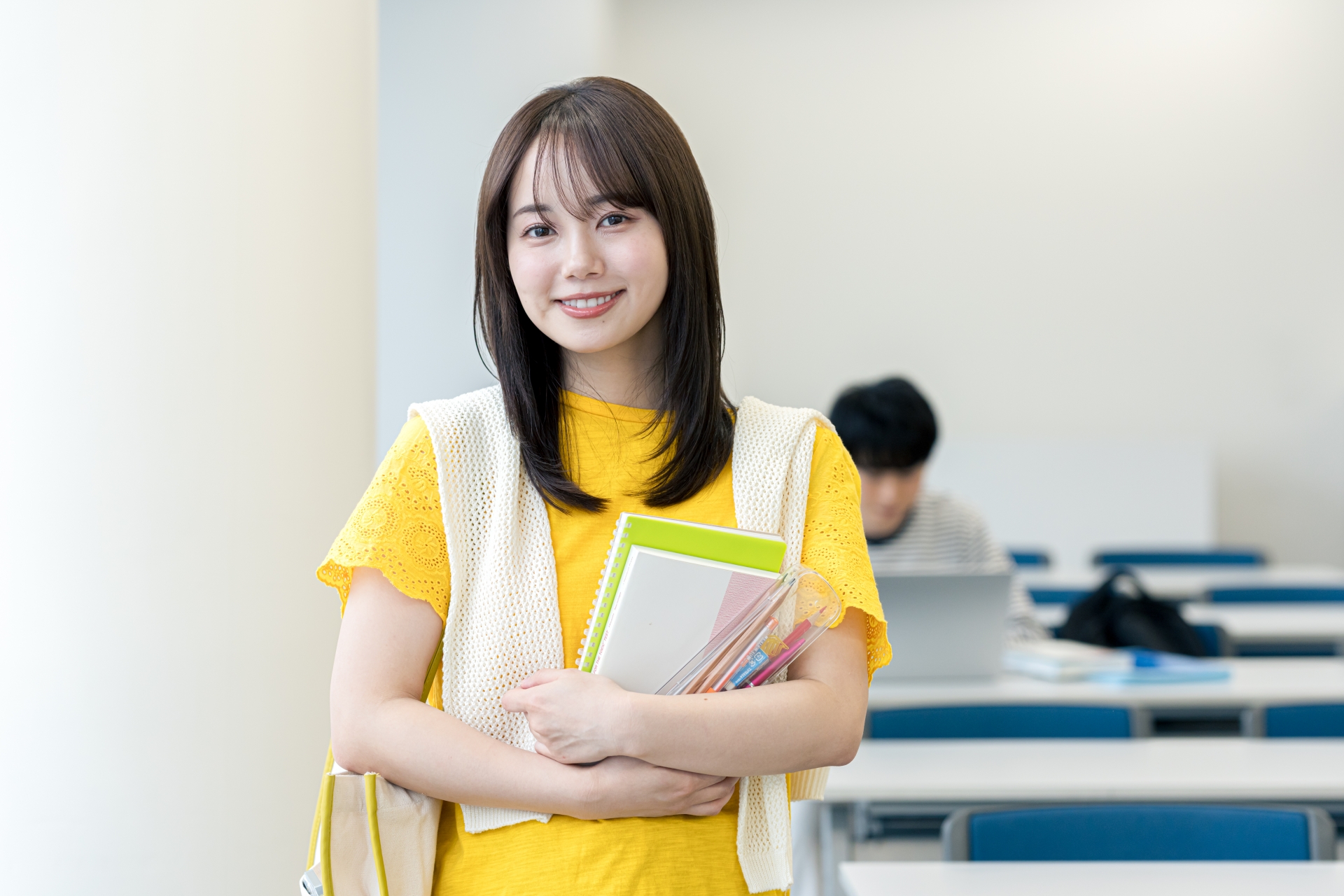 筆記用具を持った黄色い服の女性