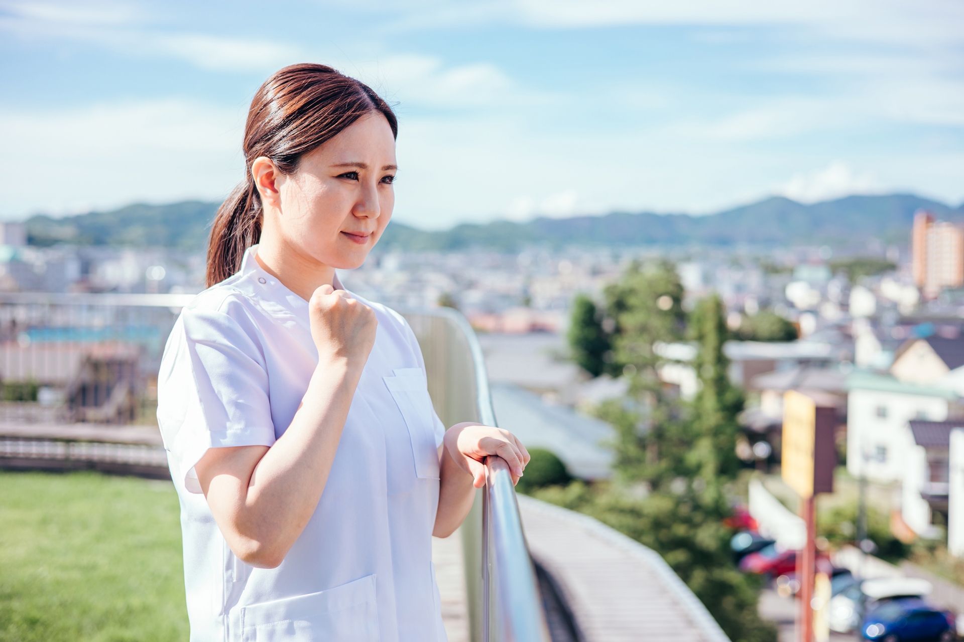 ベランダでガッツポーズをする白衣の女性