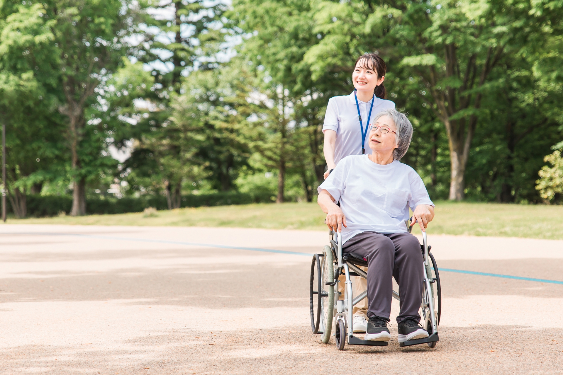 高齢女性の車椅子を押すヘルパー