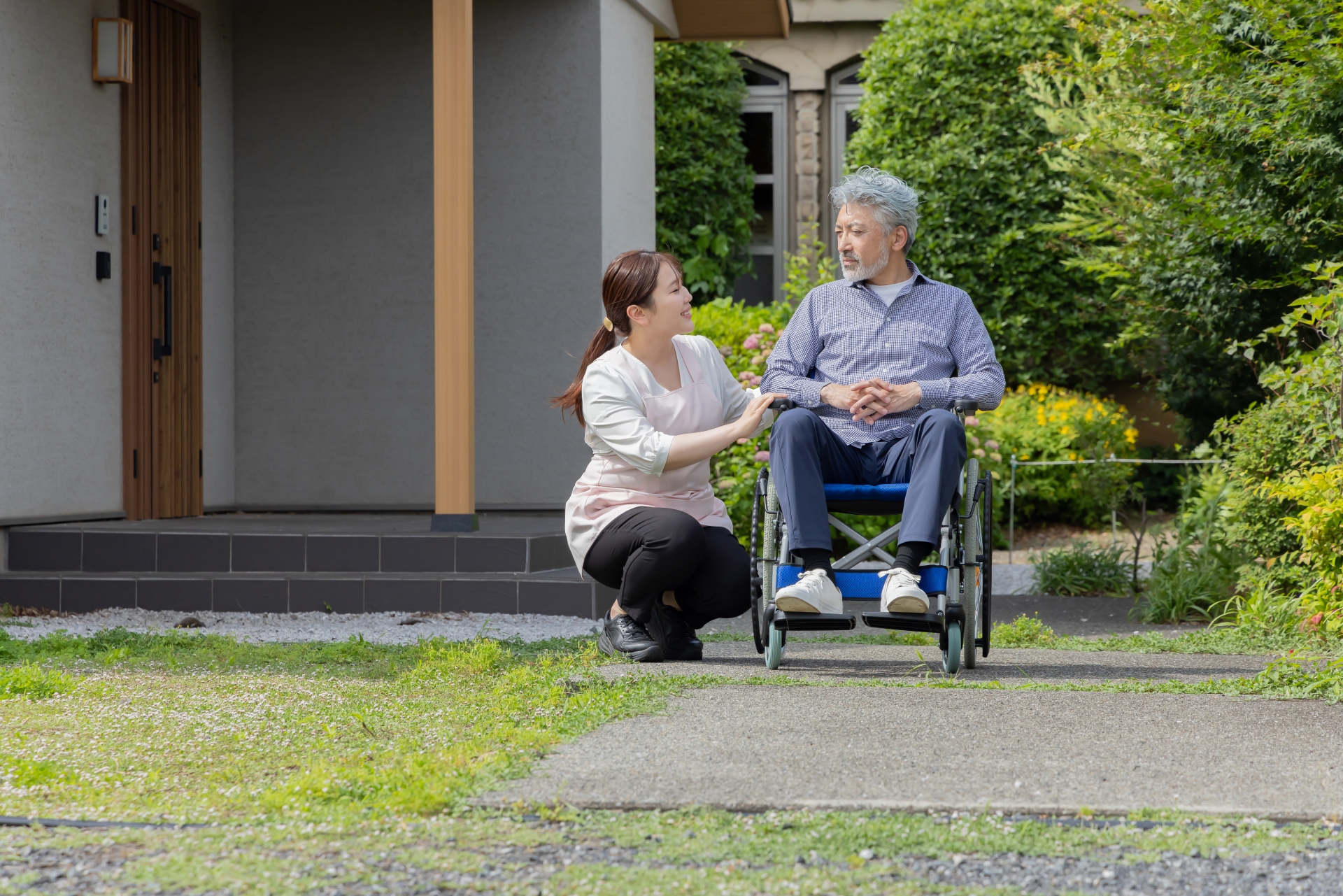 庭で車椅子に乗るシニア男性と介護士