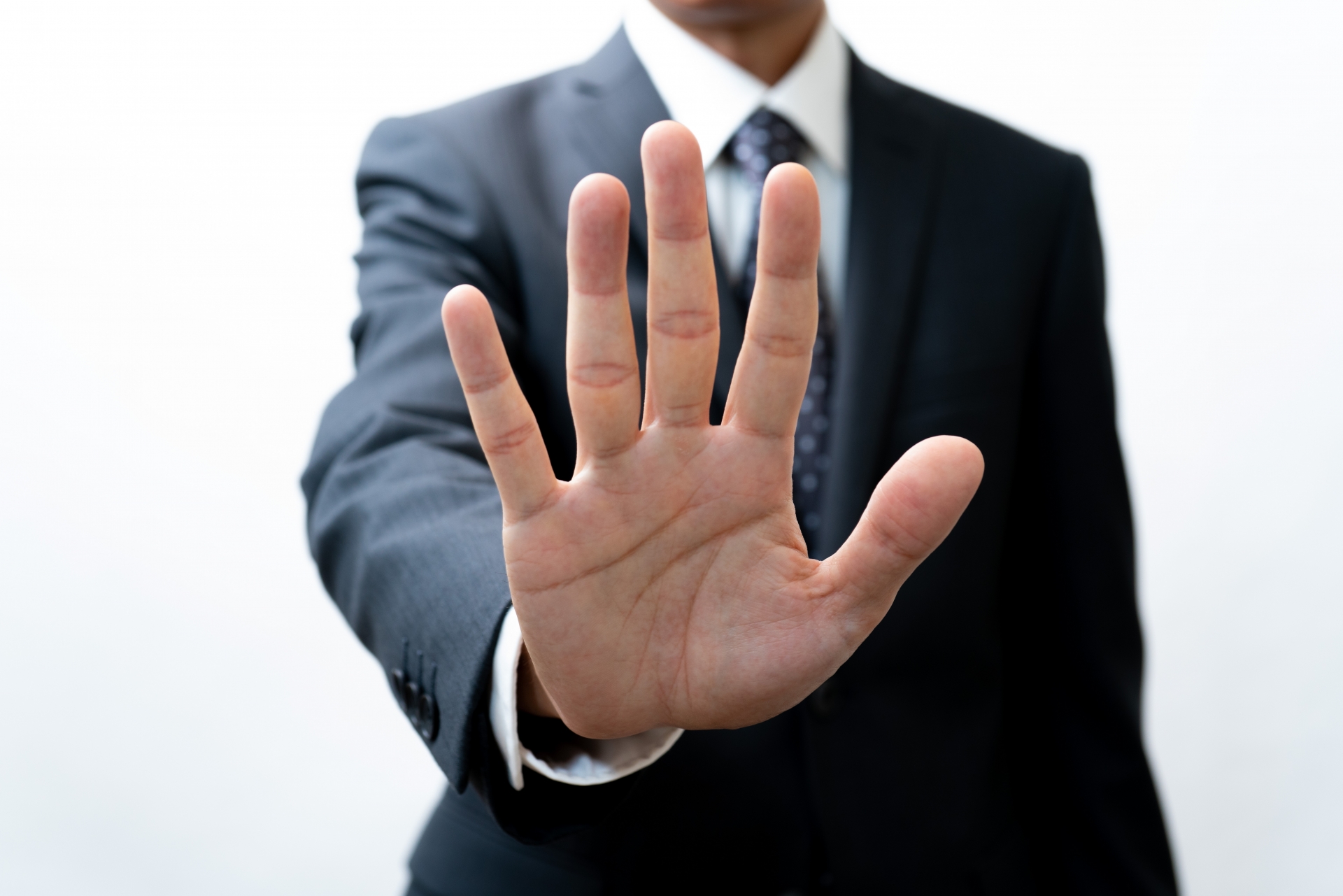手のひらを前に出すスーツの男性