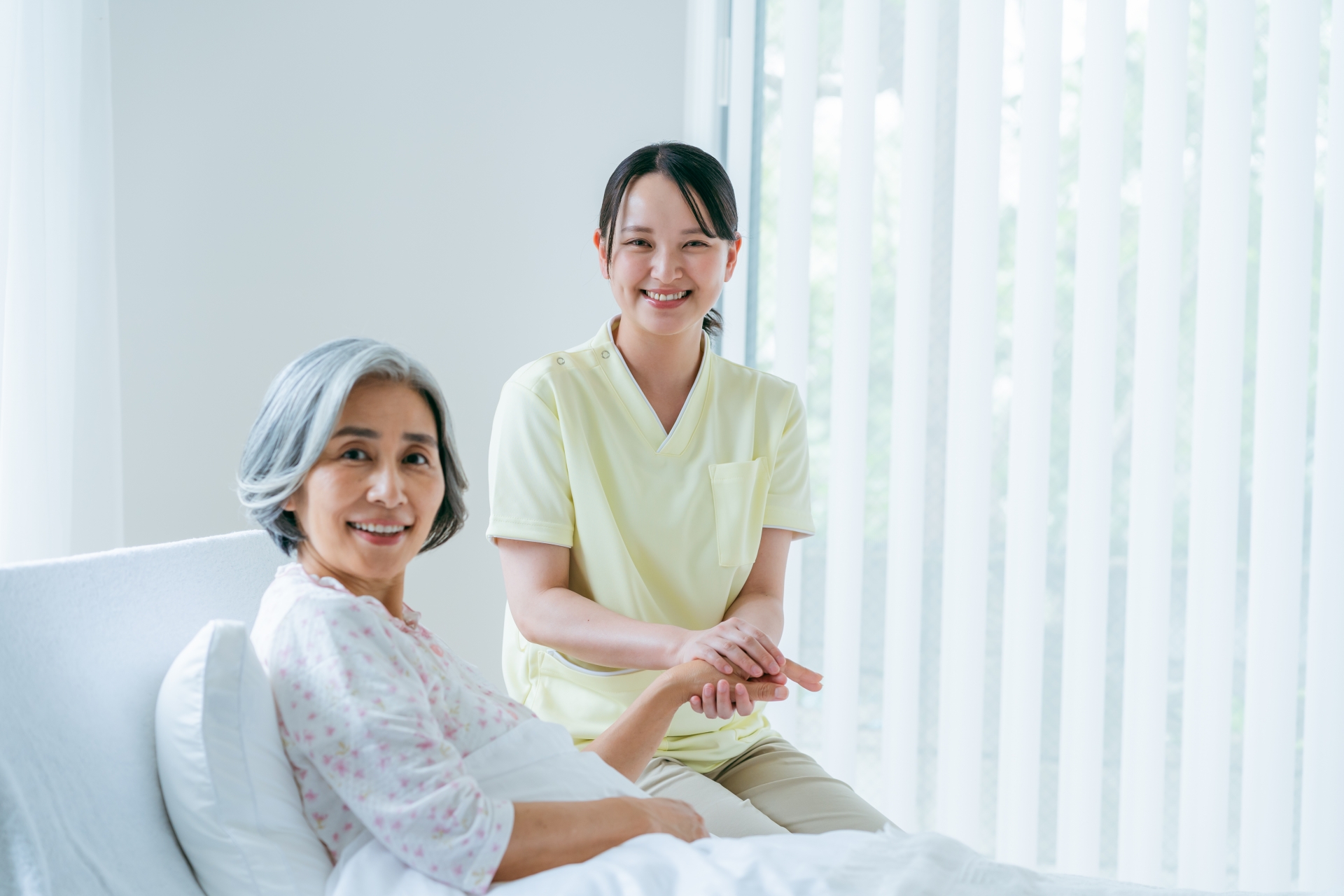 ベッドに座る女性と介護士