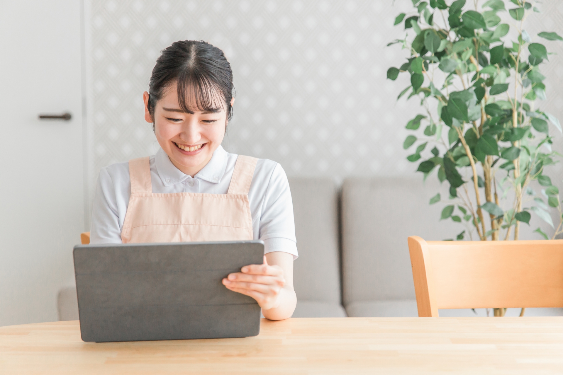 タブレットを見る笑顔のエプロンをつけた女性