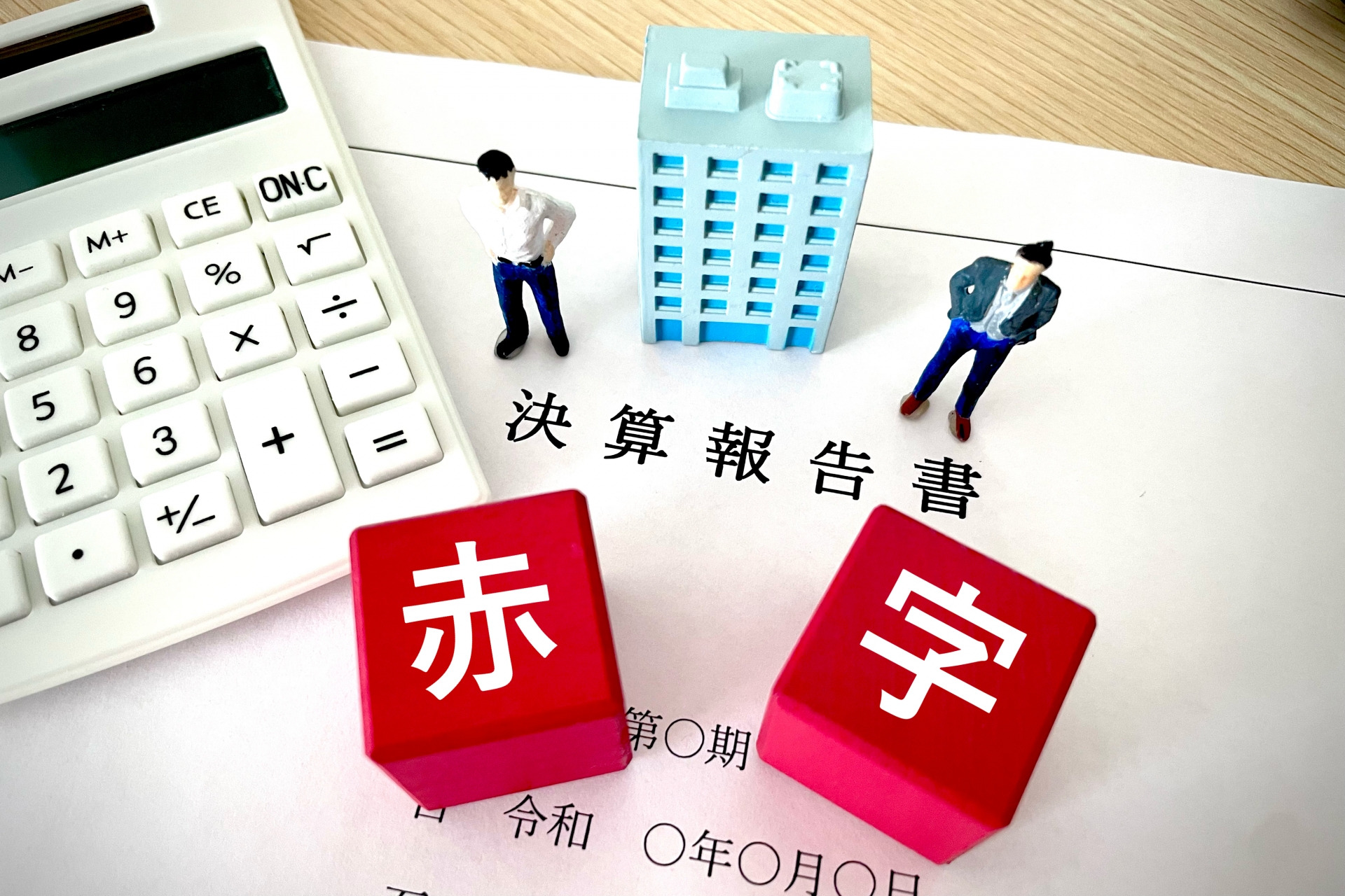 決算報告書の上にのる赤字の文字画像