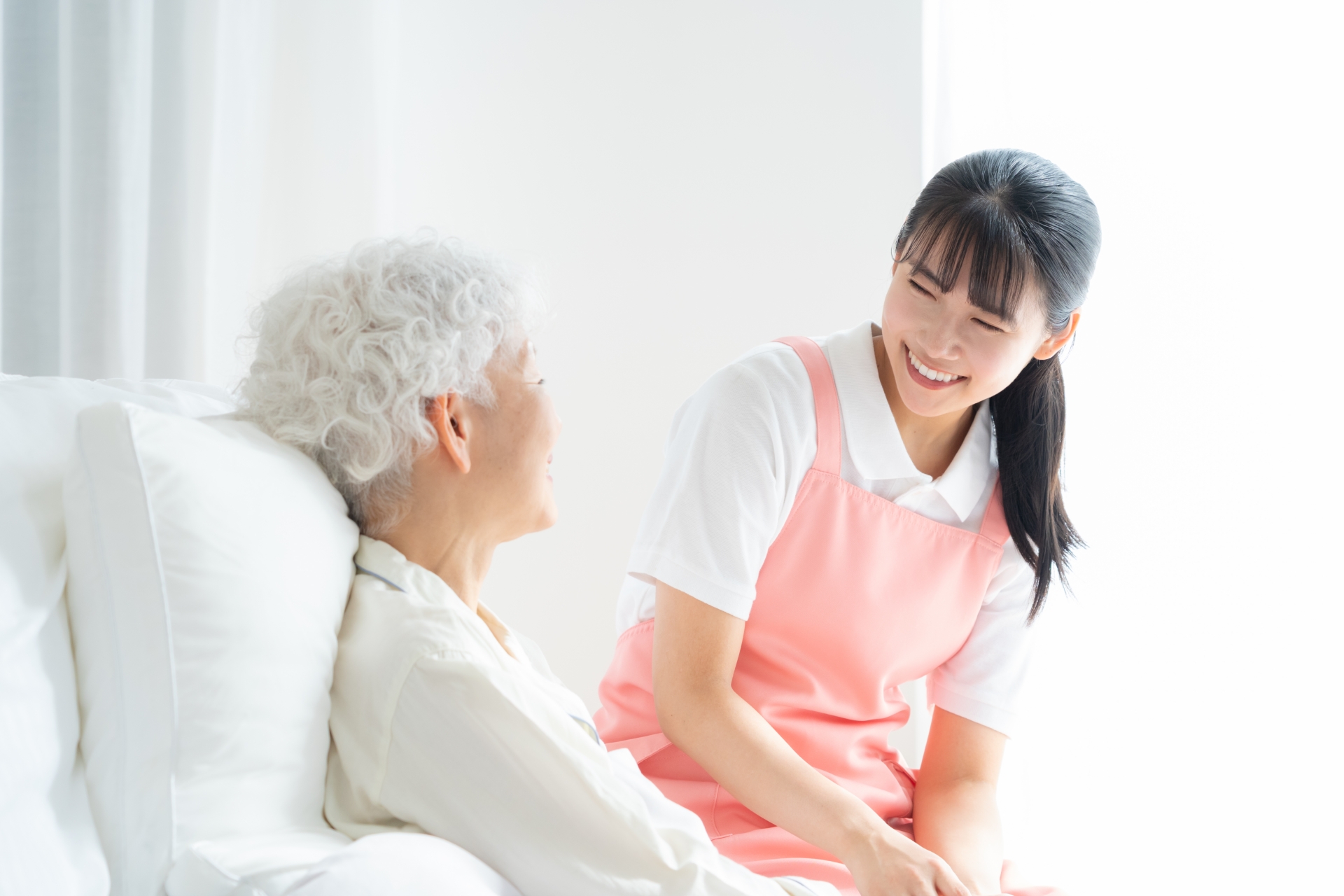 ベッドにいる高齢者と話す介護スタッフ