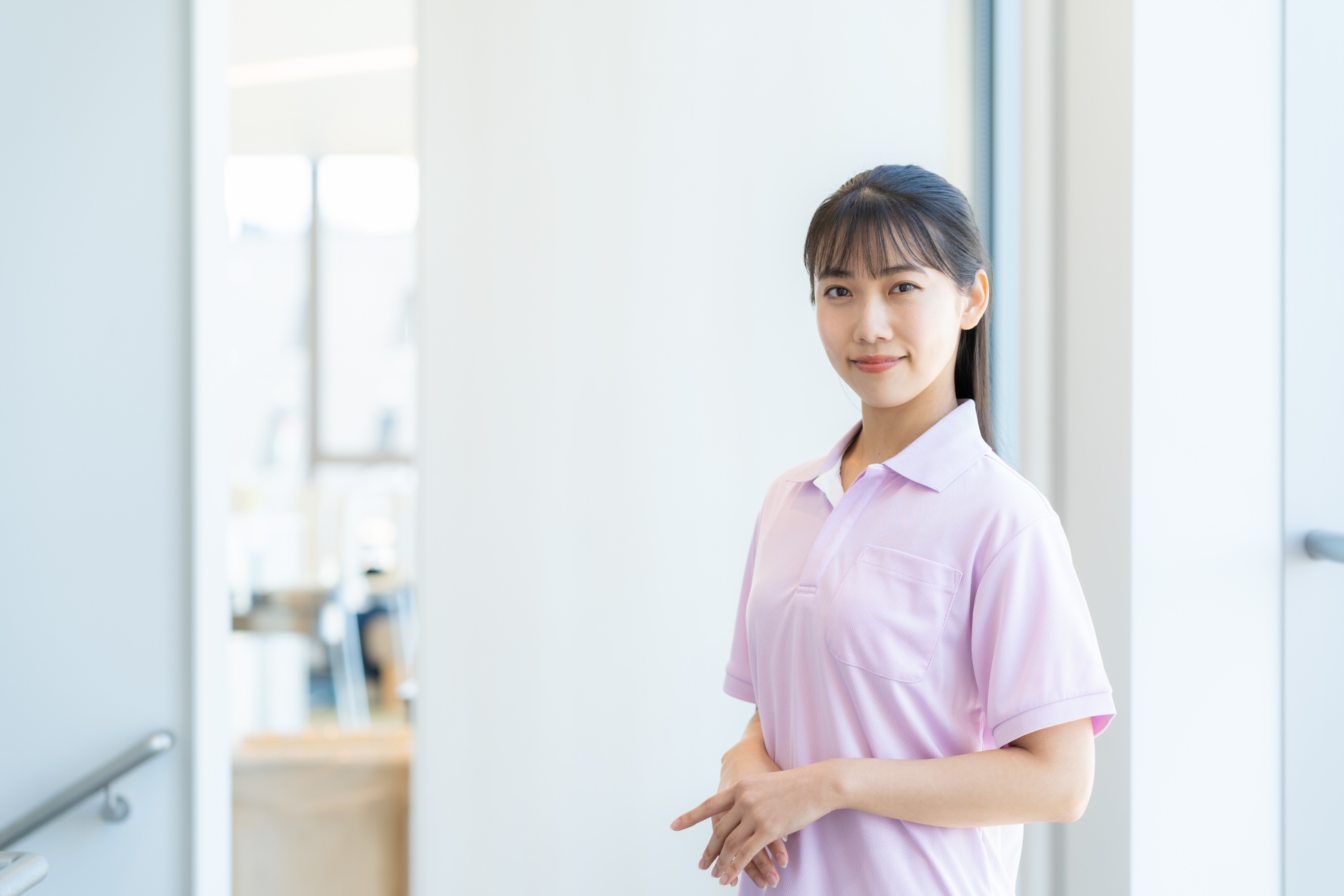 手を前に重ねて立つ介護スタッフ