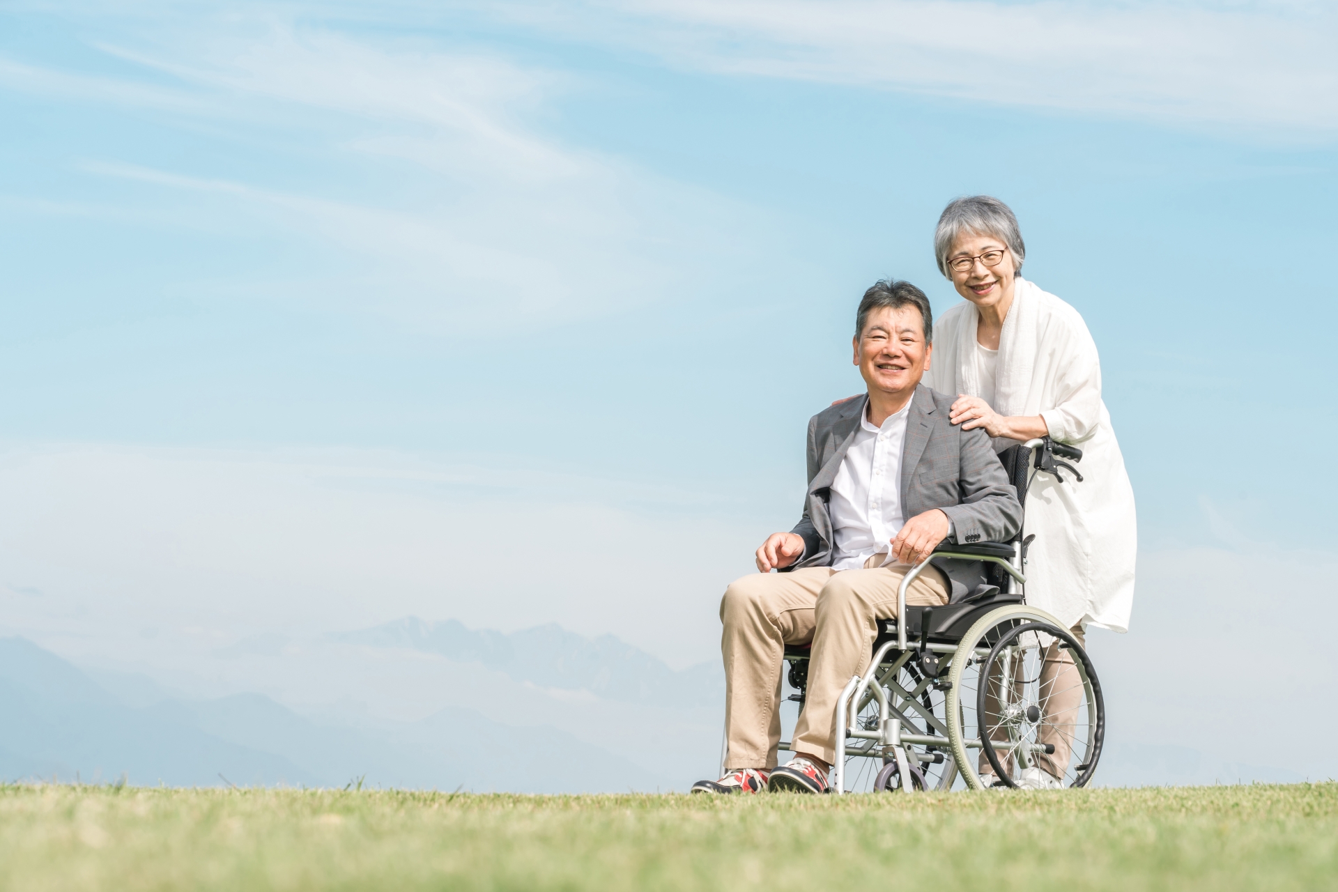 公園で車椅子に乗って散歩する高齢者夫婦