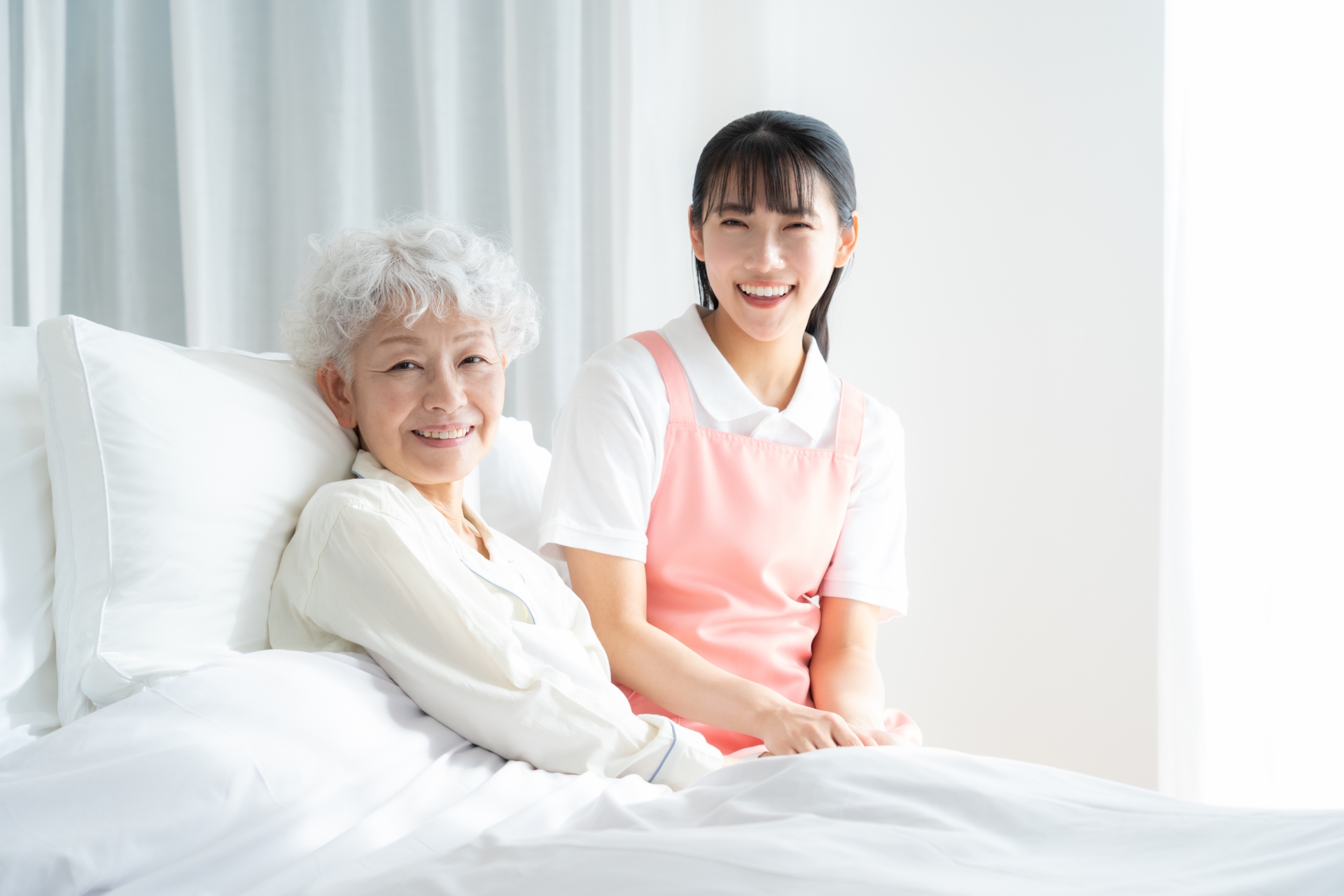 ベッドにいる高齢女性と介護士の女性