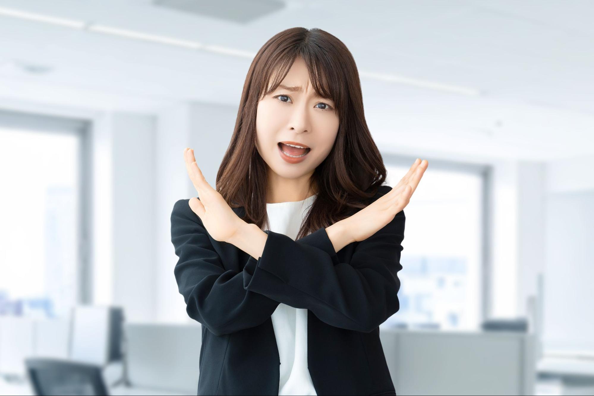 手でバツサインをする女性