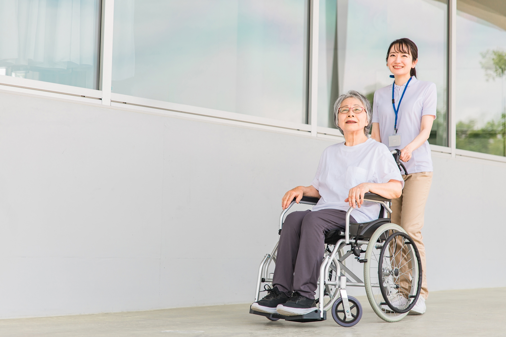 散歩する車椅子に乗る高齢者と介護士