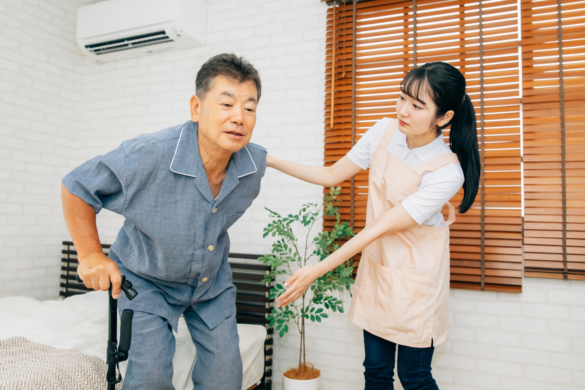 杖を使う高齢者男性と女性スタッフ