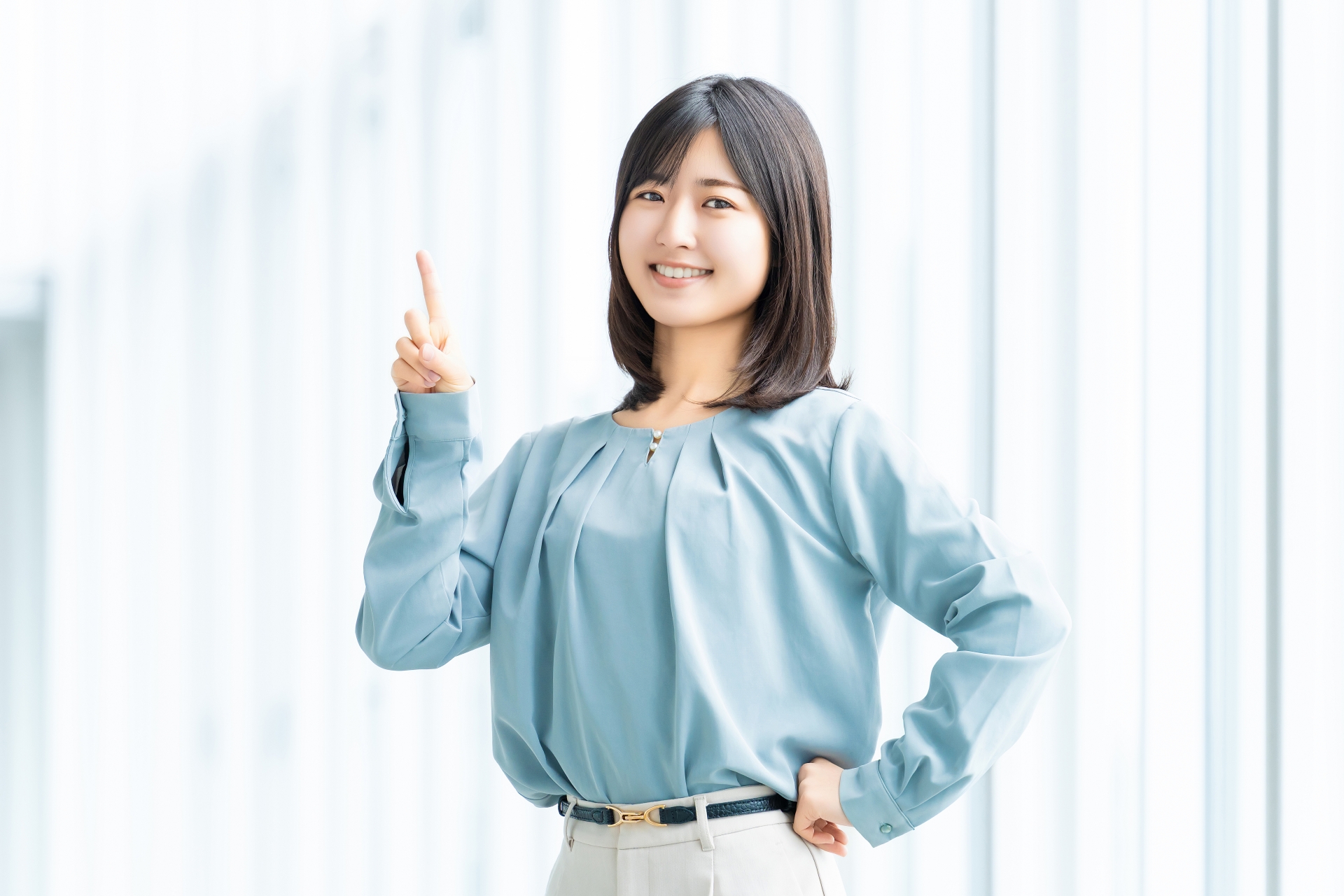 人差し指を立てて案内する笑顔の女性