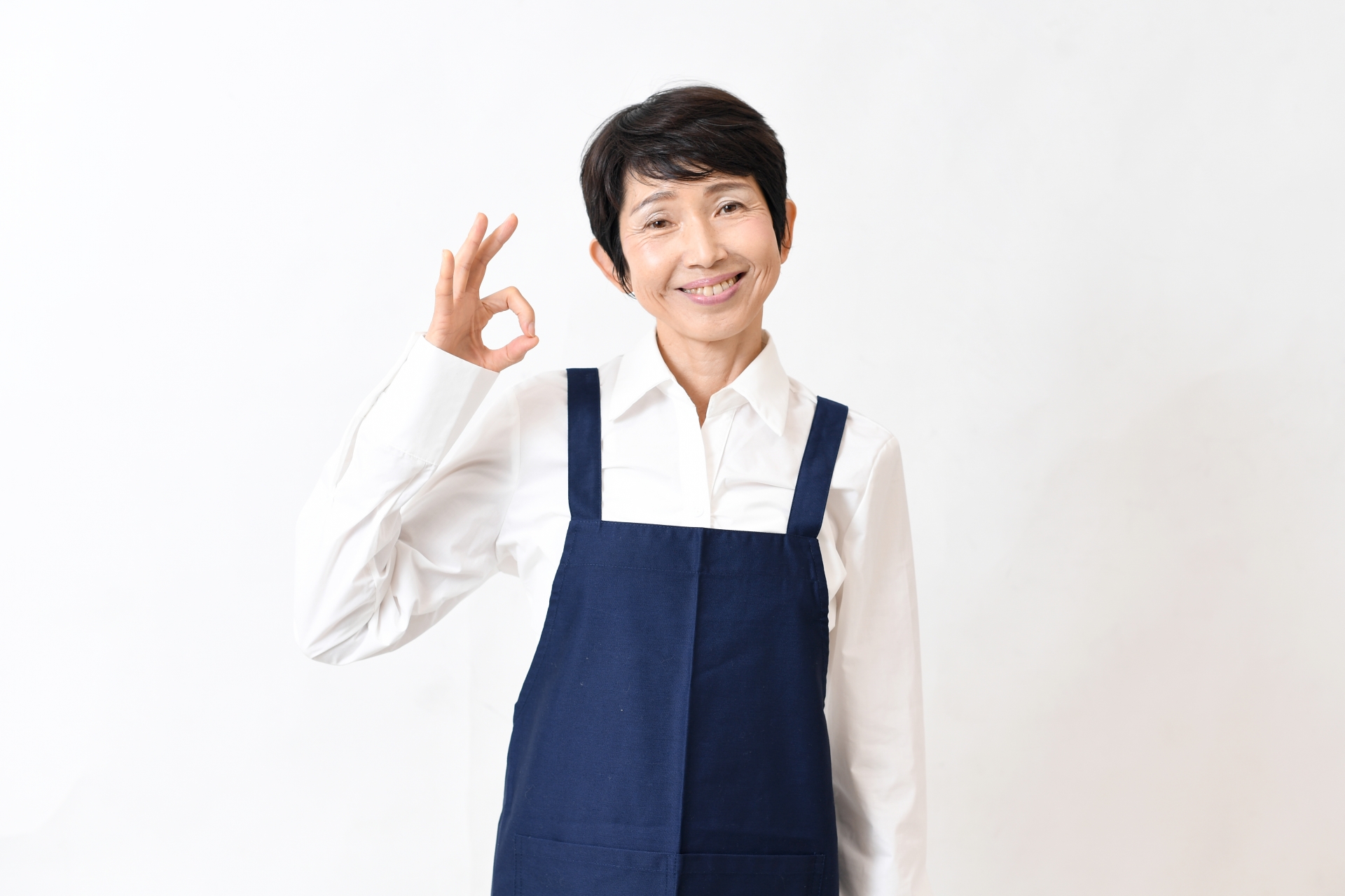 OKポーズをするエプロン姿の中高年女性