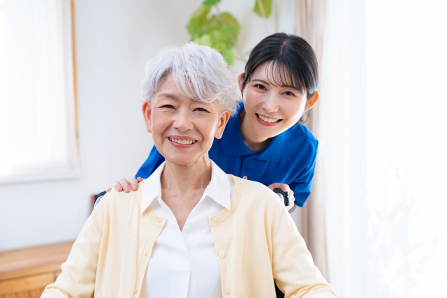 高齢者の背後から顔を出す笑顔の介護士