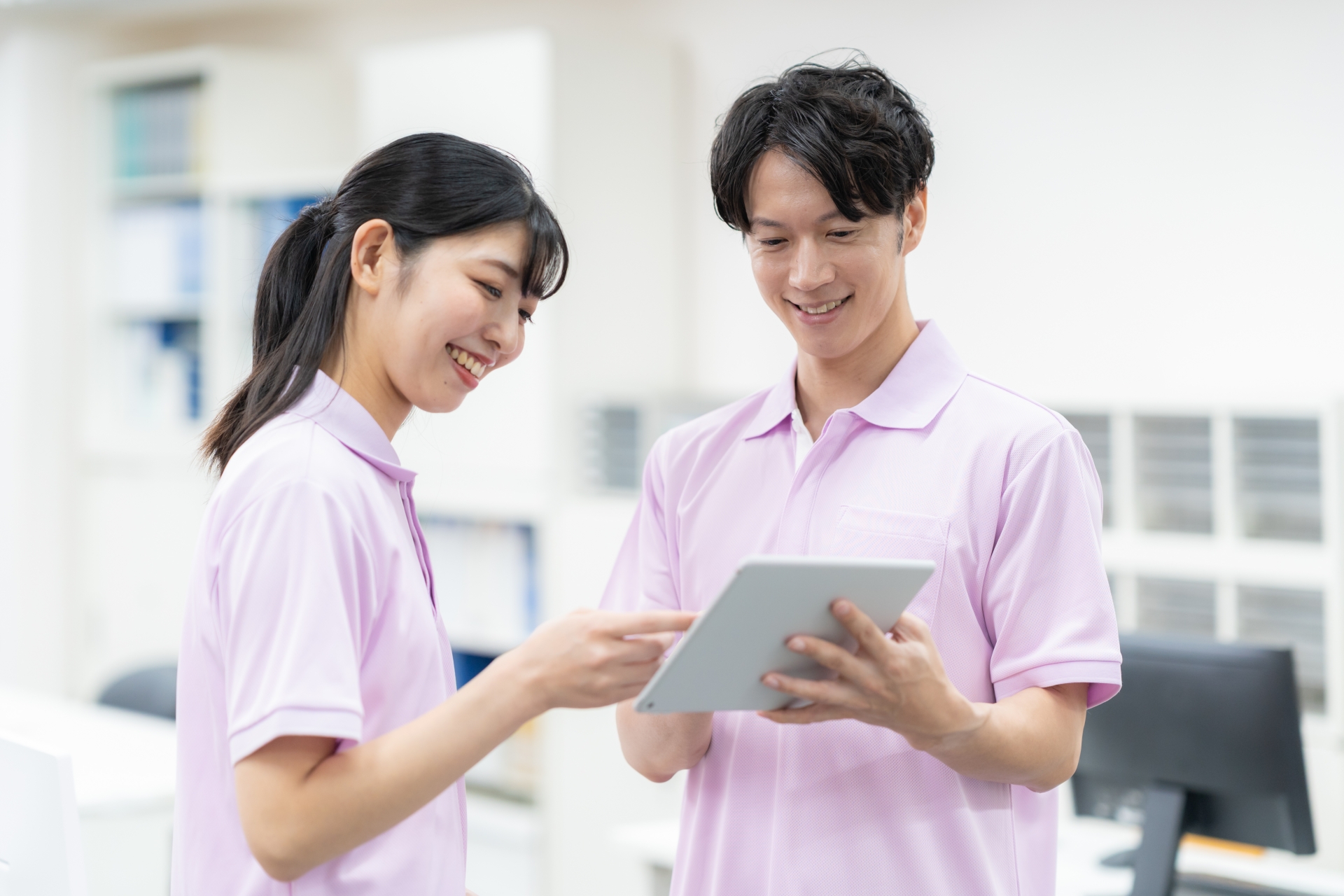 タブレット画面をチェックする男女の介護士