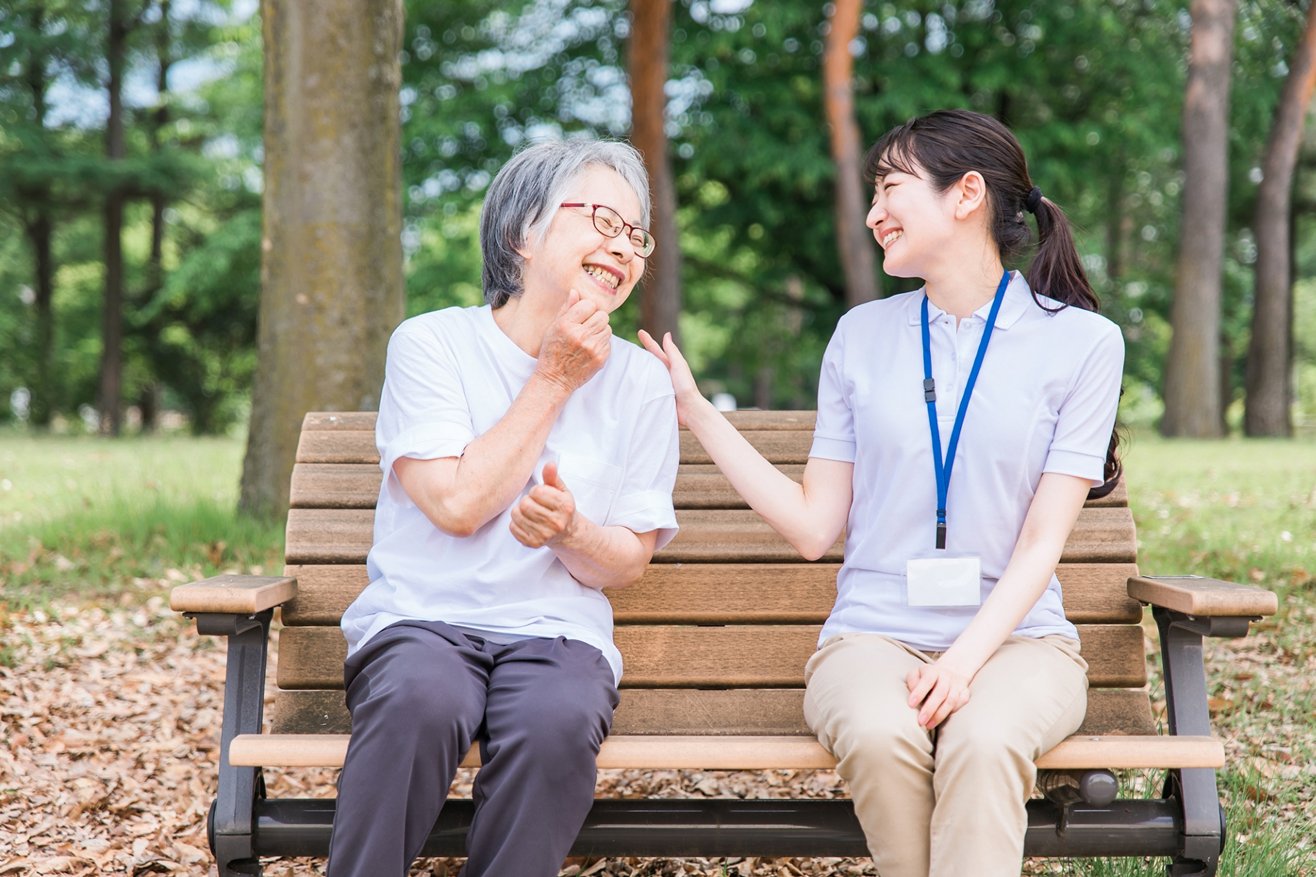 ベンチで話す介護士と高齢女性