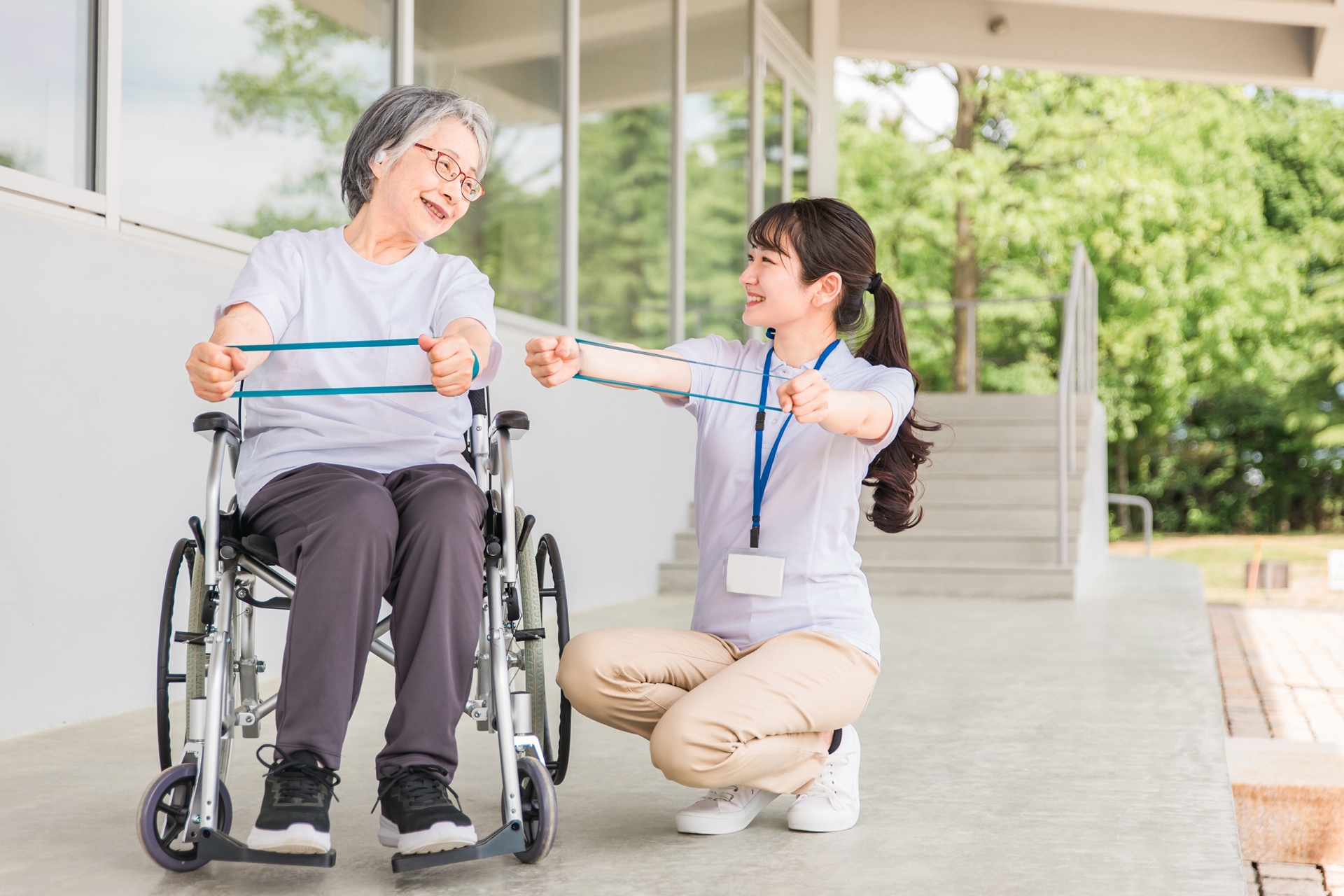 ゴムを伸ばして体操する高齢者と介護士