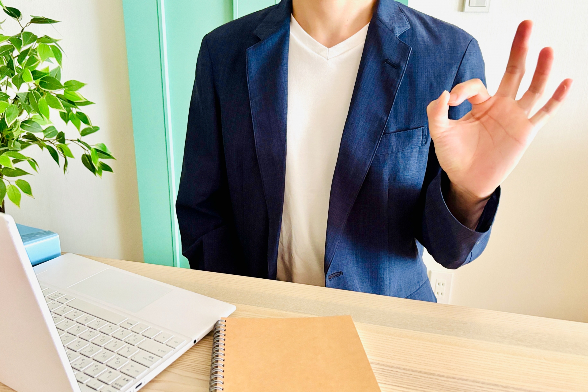 パソコンの前に座ってOKサインをする男性