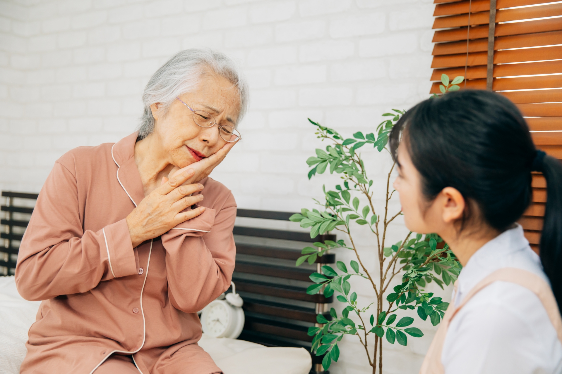 痛がる高齢者女性と介護士