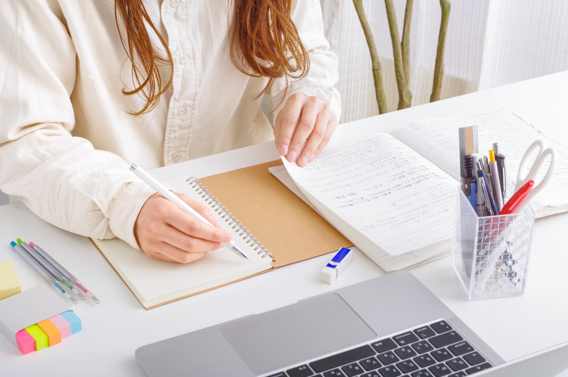 ノートに文字を書いて勉強する女性