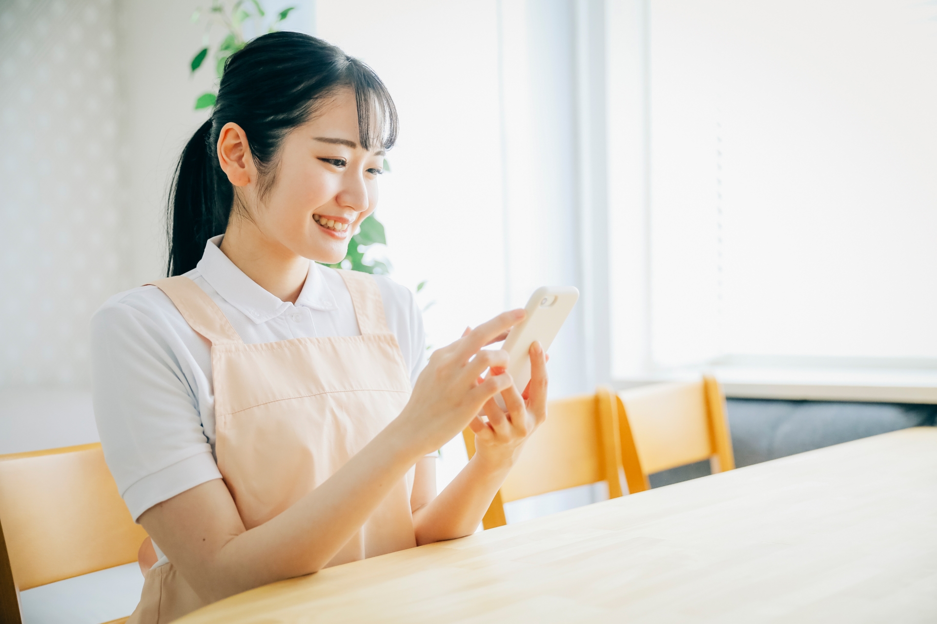 スマホを使うエプロン姿の女性