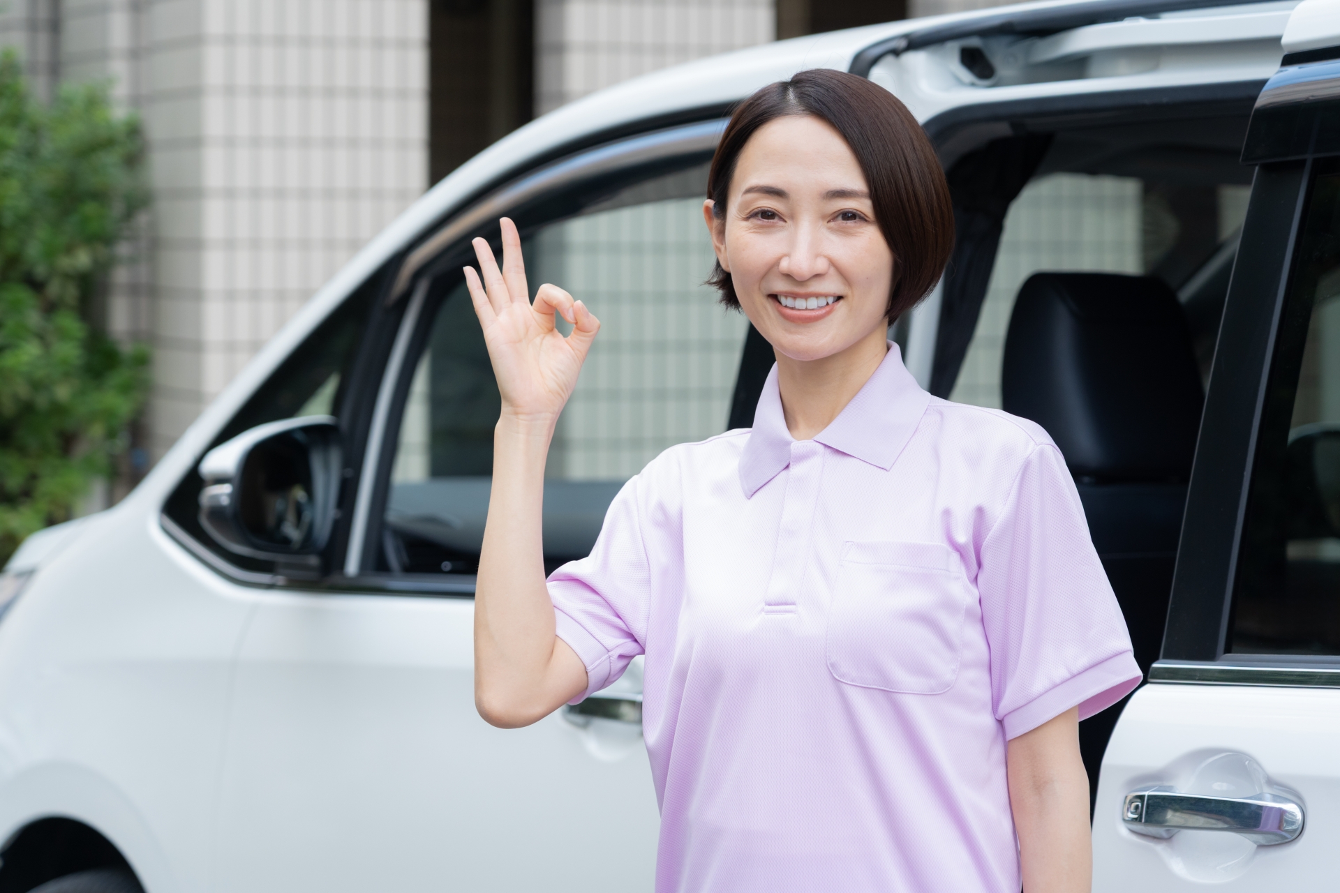 車の横でOKサインをする人