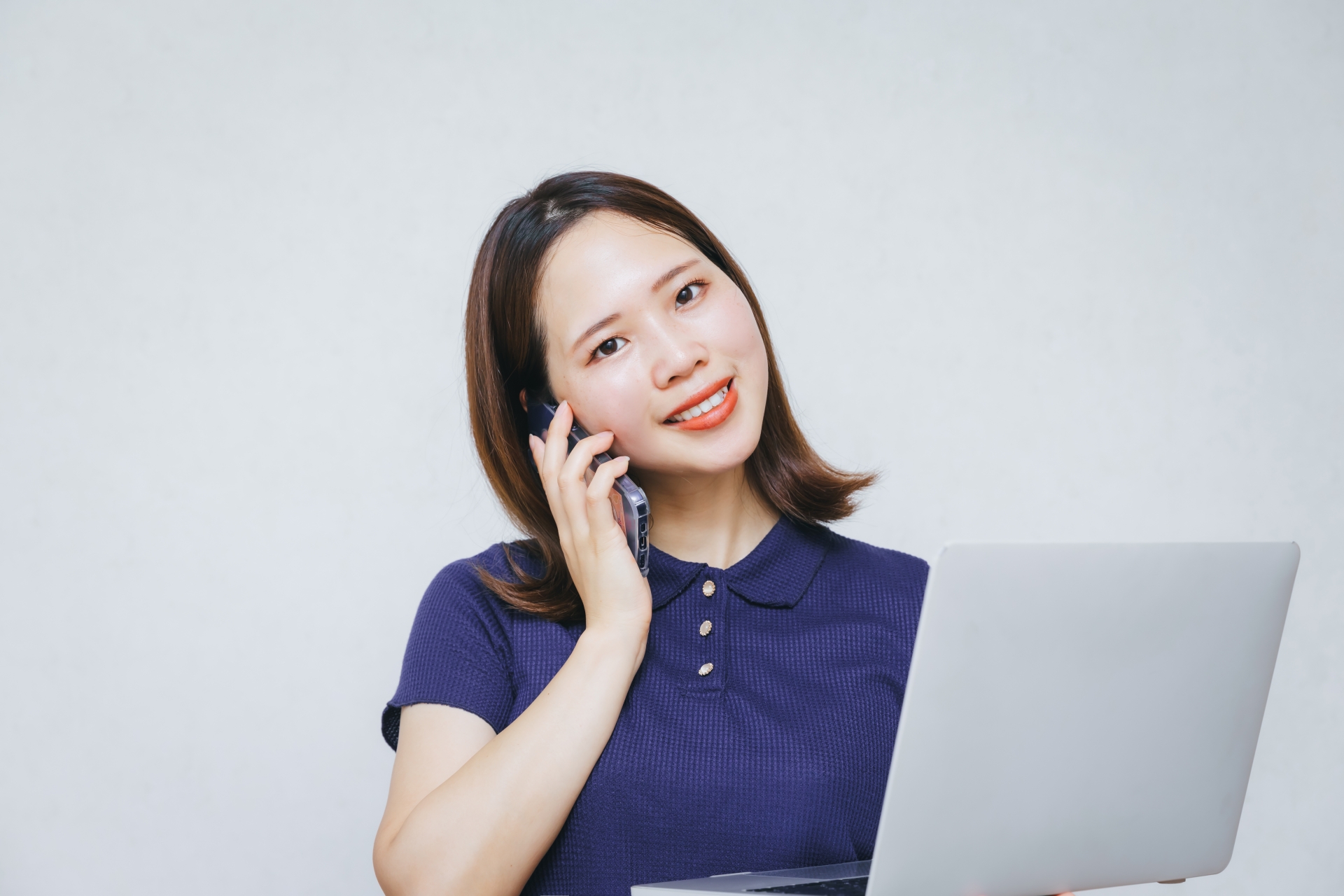 パソコンの前で電話する女性