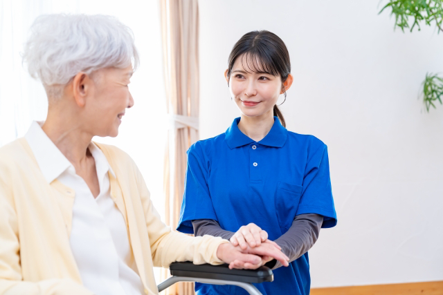 車椅子の女性を見つめる介護士
