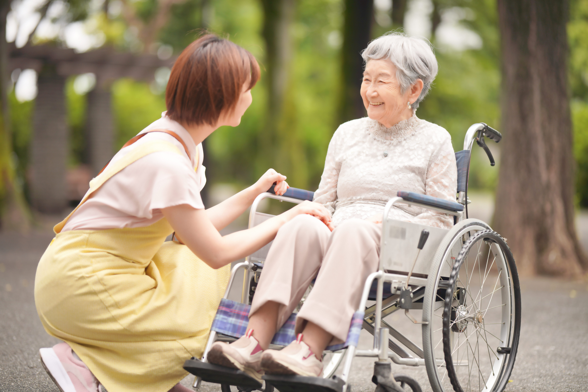 車椅子の女性の目線で話をする介護士