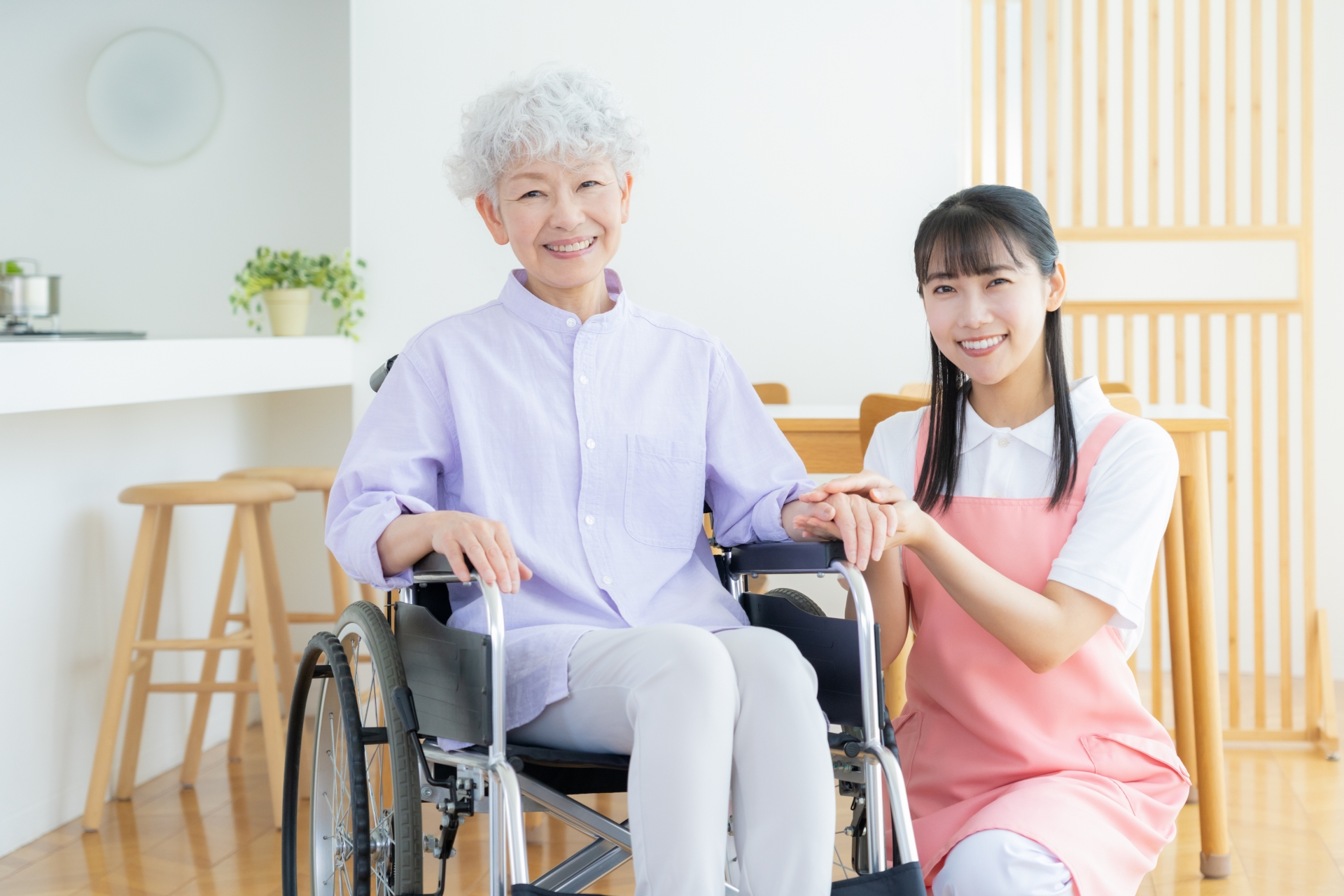 車椅子の女性のそばに座る笑顔のスタッフ