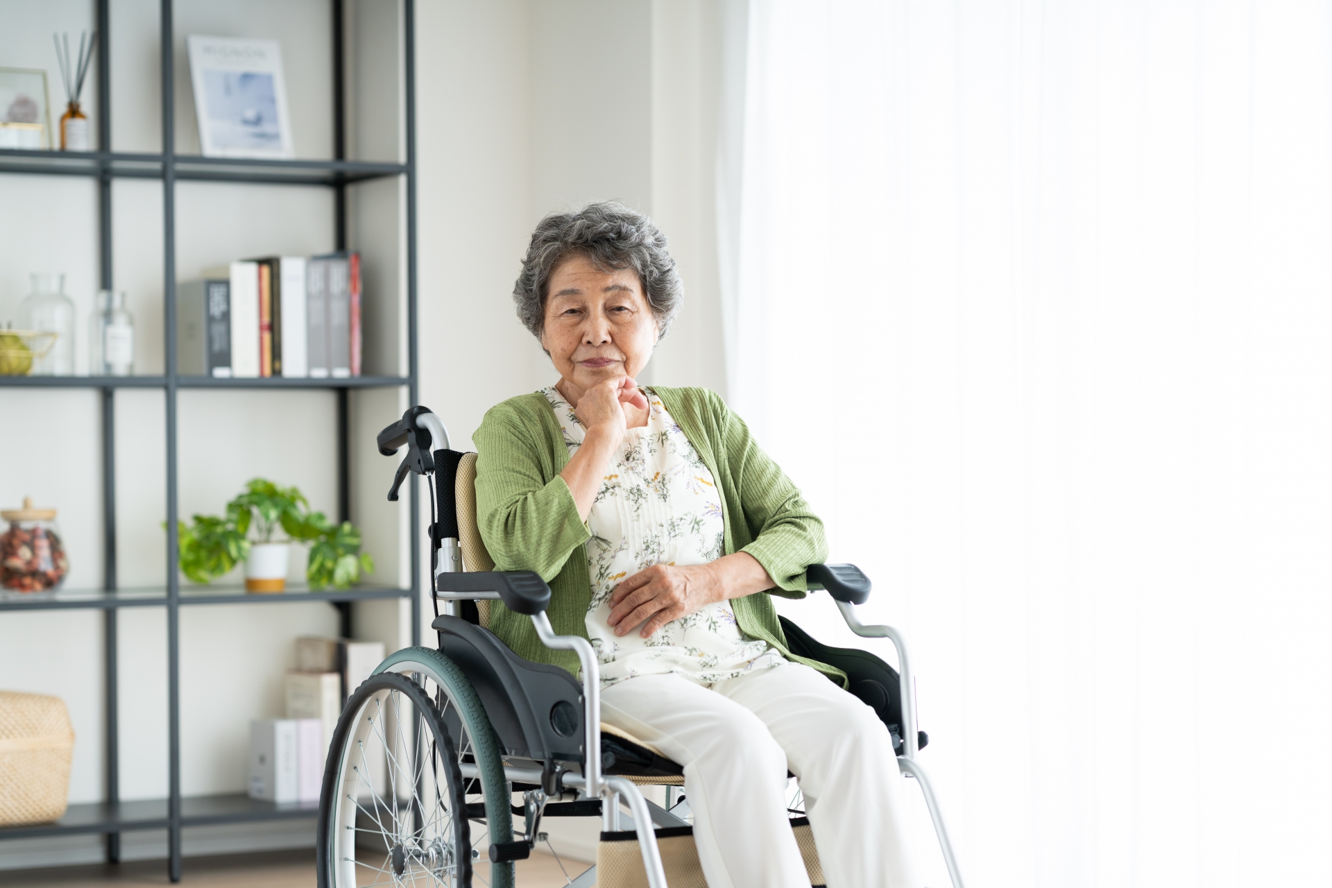 悩む車椅子のシニアの女性