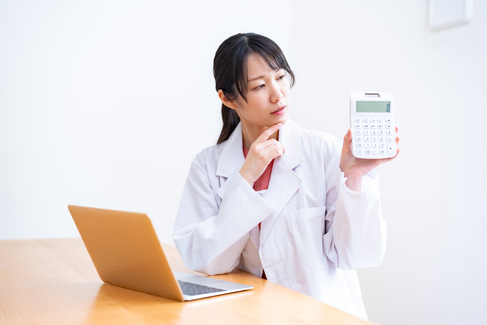 電卓を持ち悩む女性医師