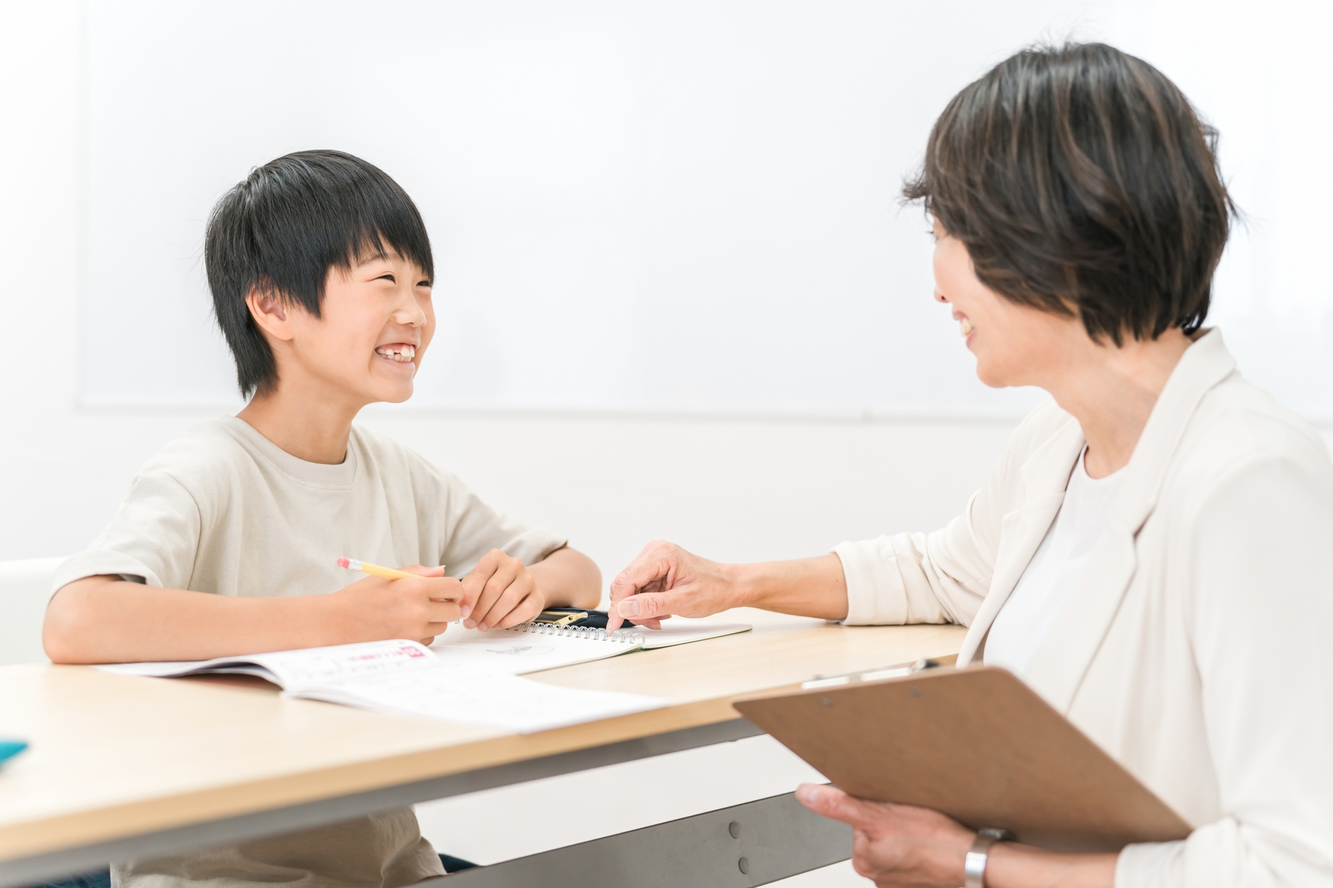塾・学童で勉強する小学生と女性講師・先生