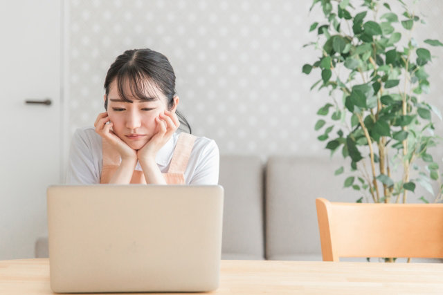 パソコンの前で考え込む女性