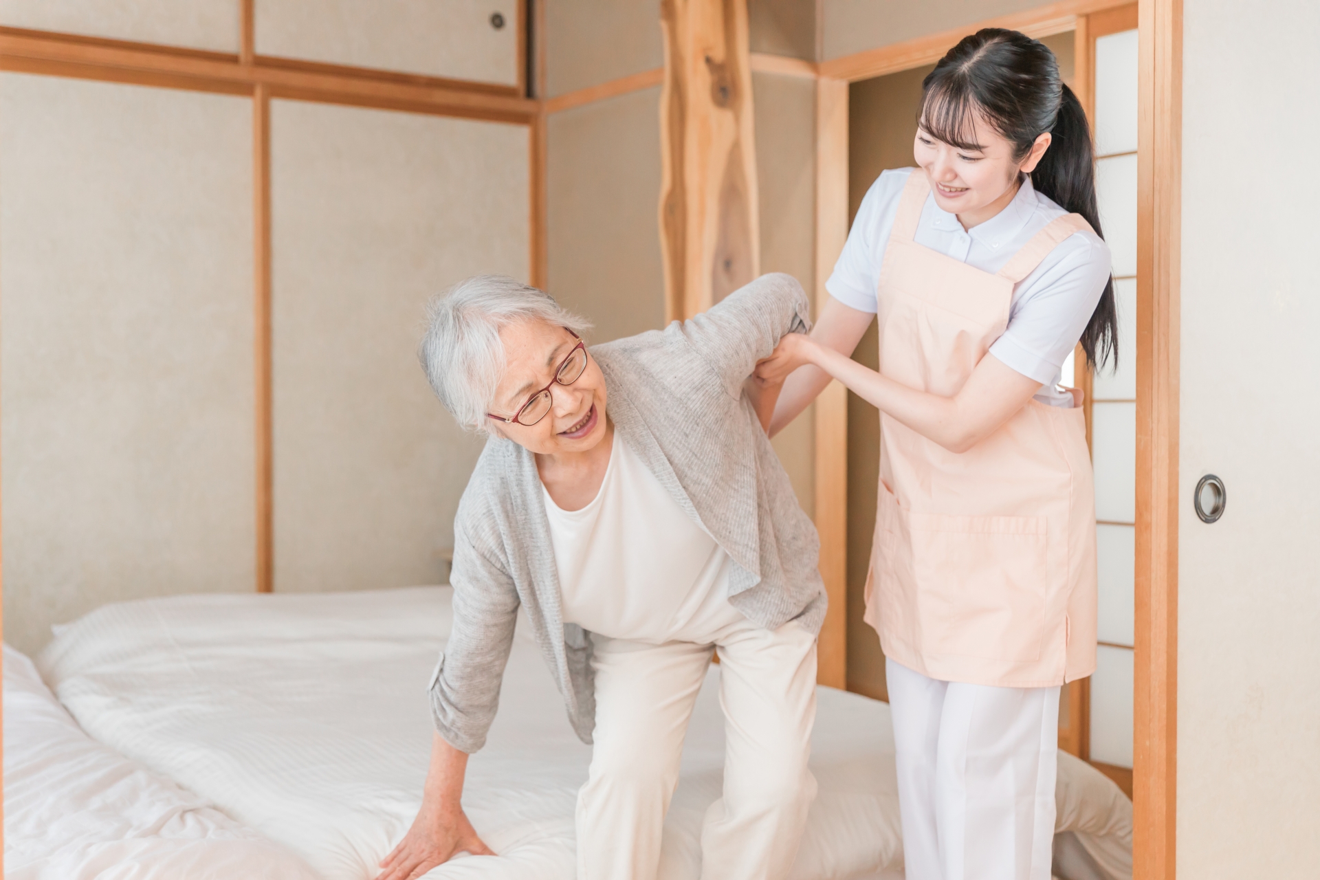 腰を抑えるシニアの女性を支えるスタッフ