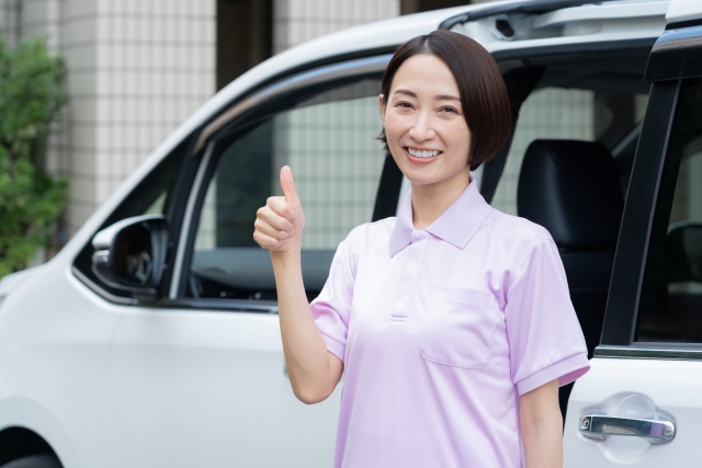 車の横で親指を立てる介護士