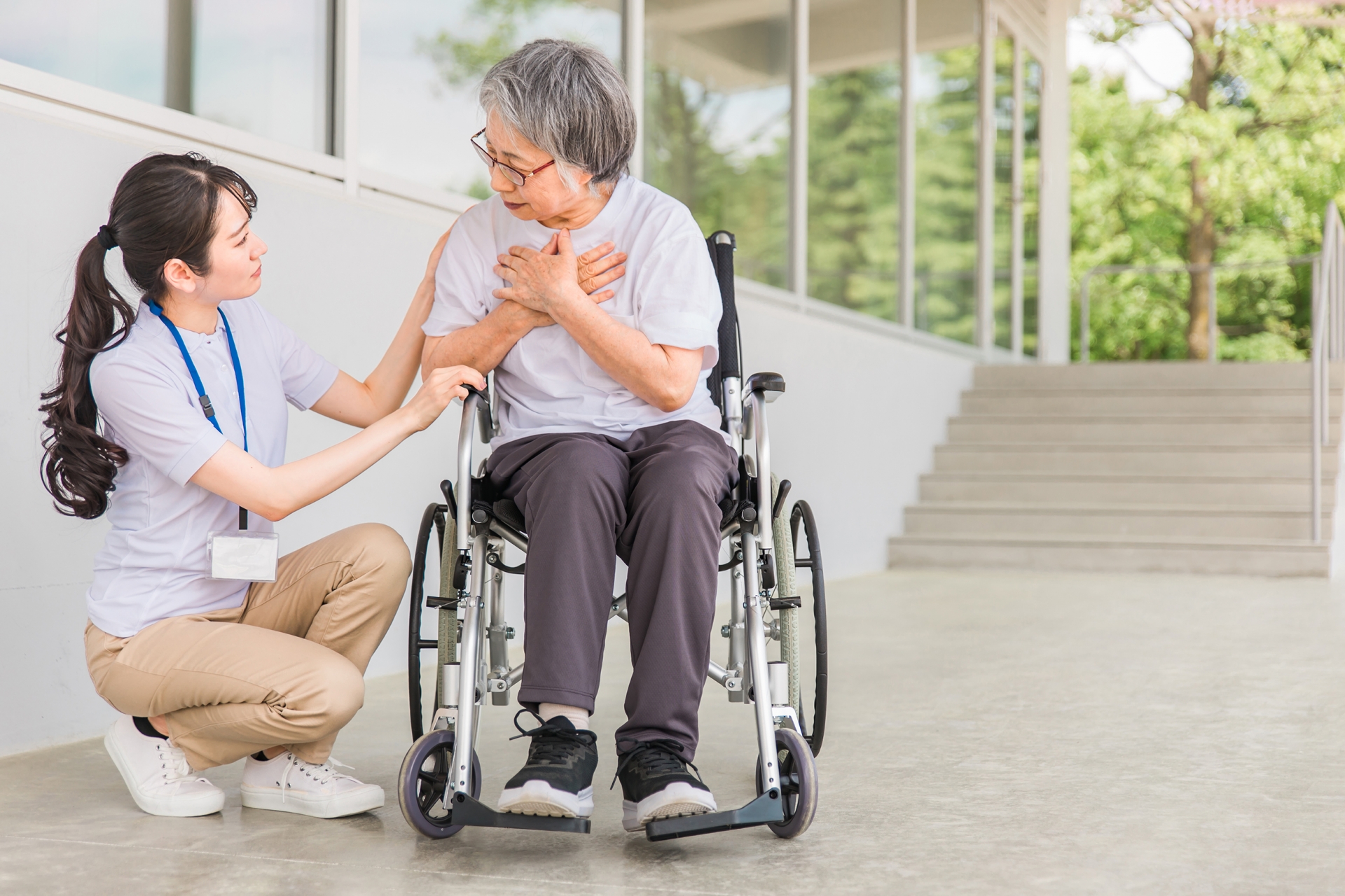 介護士と胸をおさえる車椅子に乗った高齢者