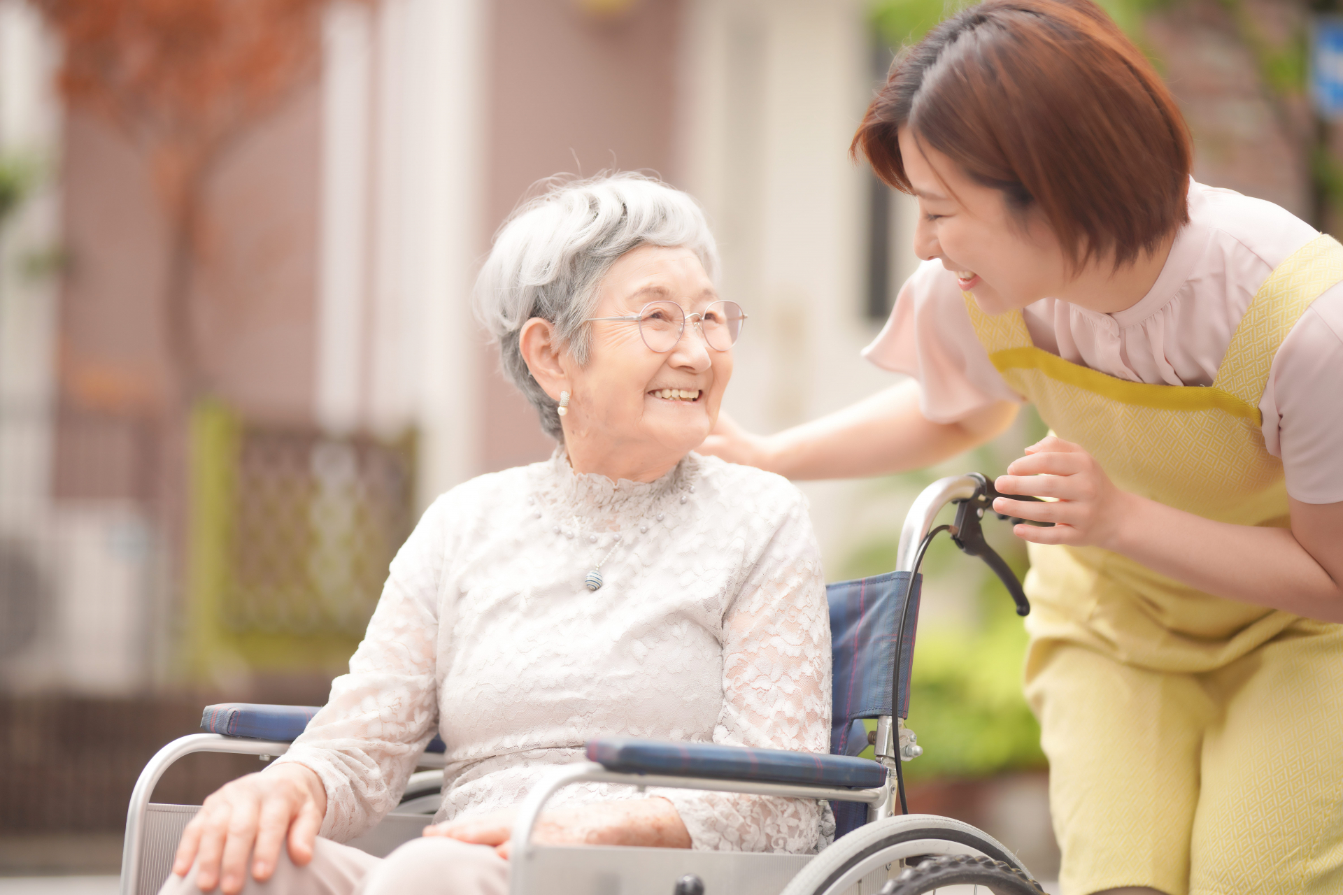 車椅子の女性に後ろから話しかける女性スタッフ