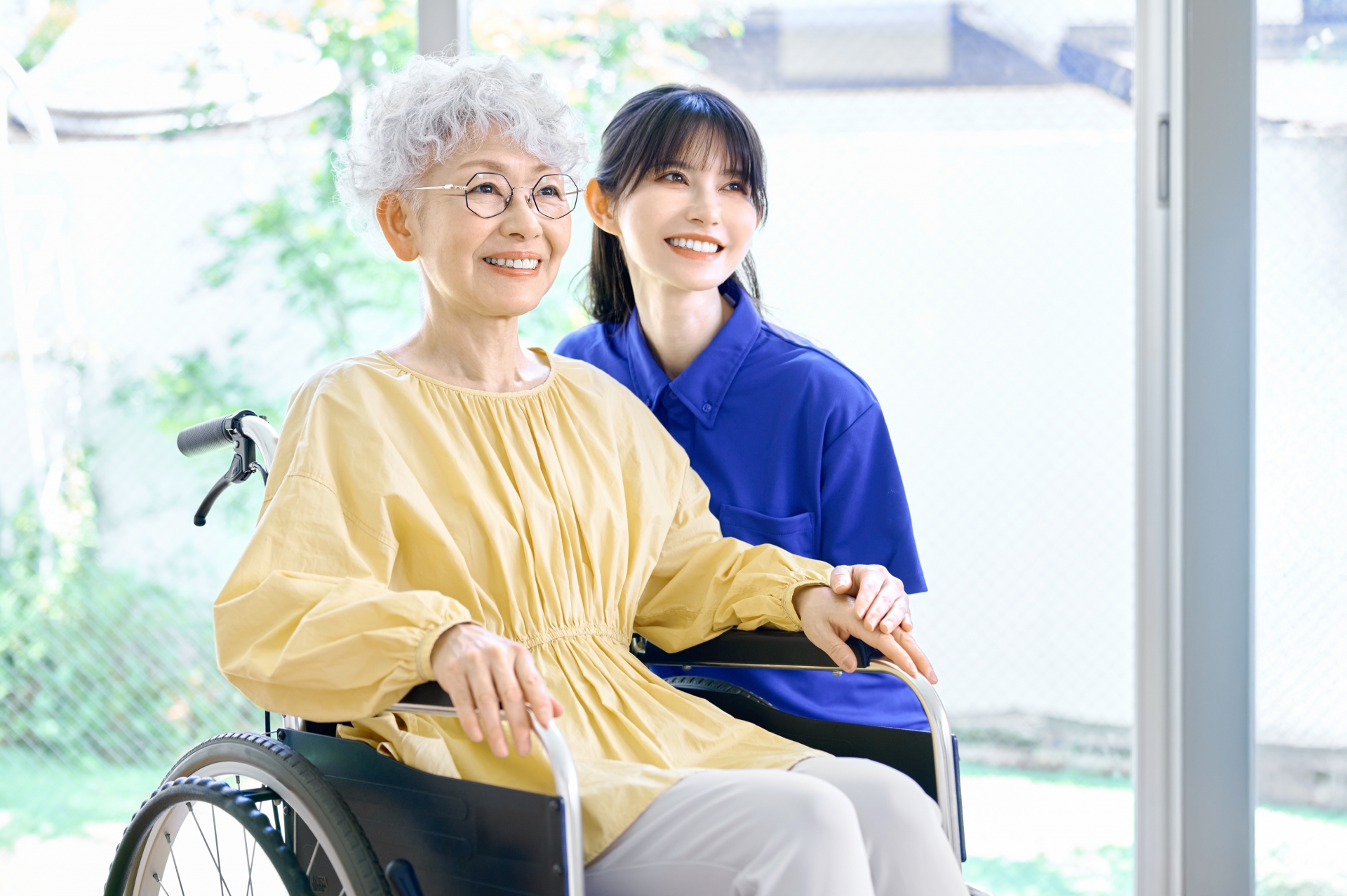 車椅子の女性と寄り添う介護士