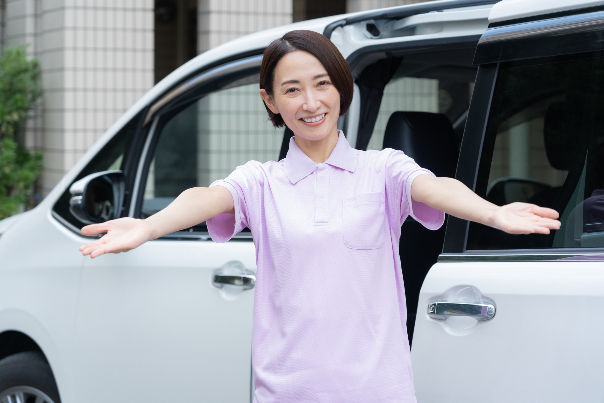 車と両手を広げる女性スタッフ