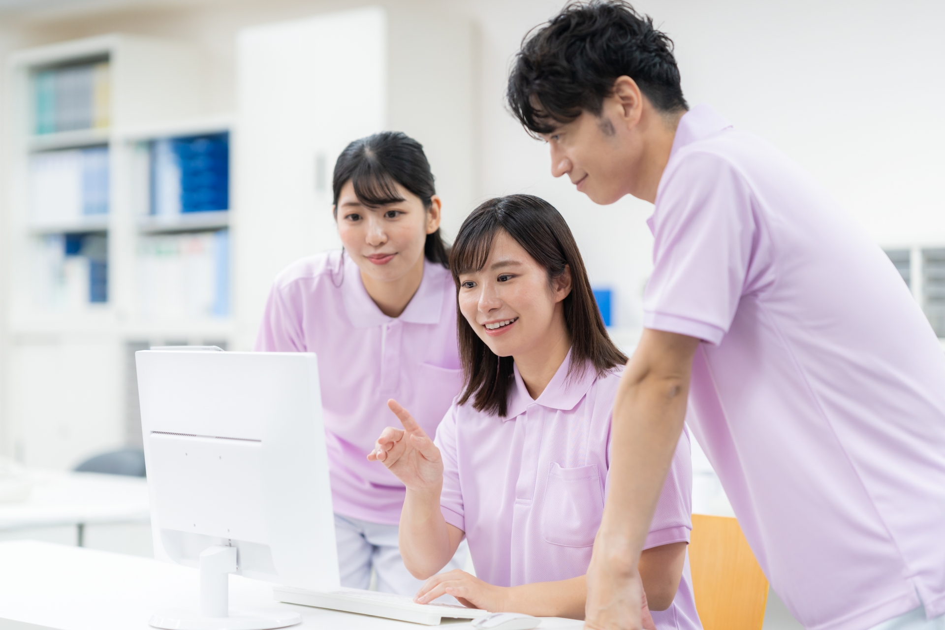 パソコンを見る男女の介護士たち