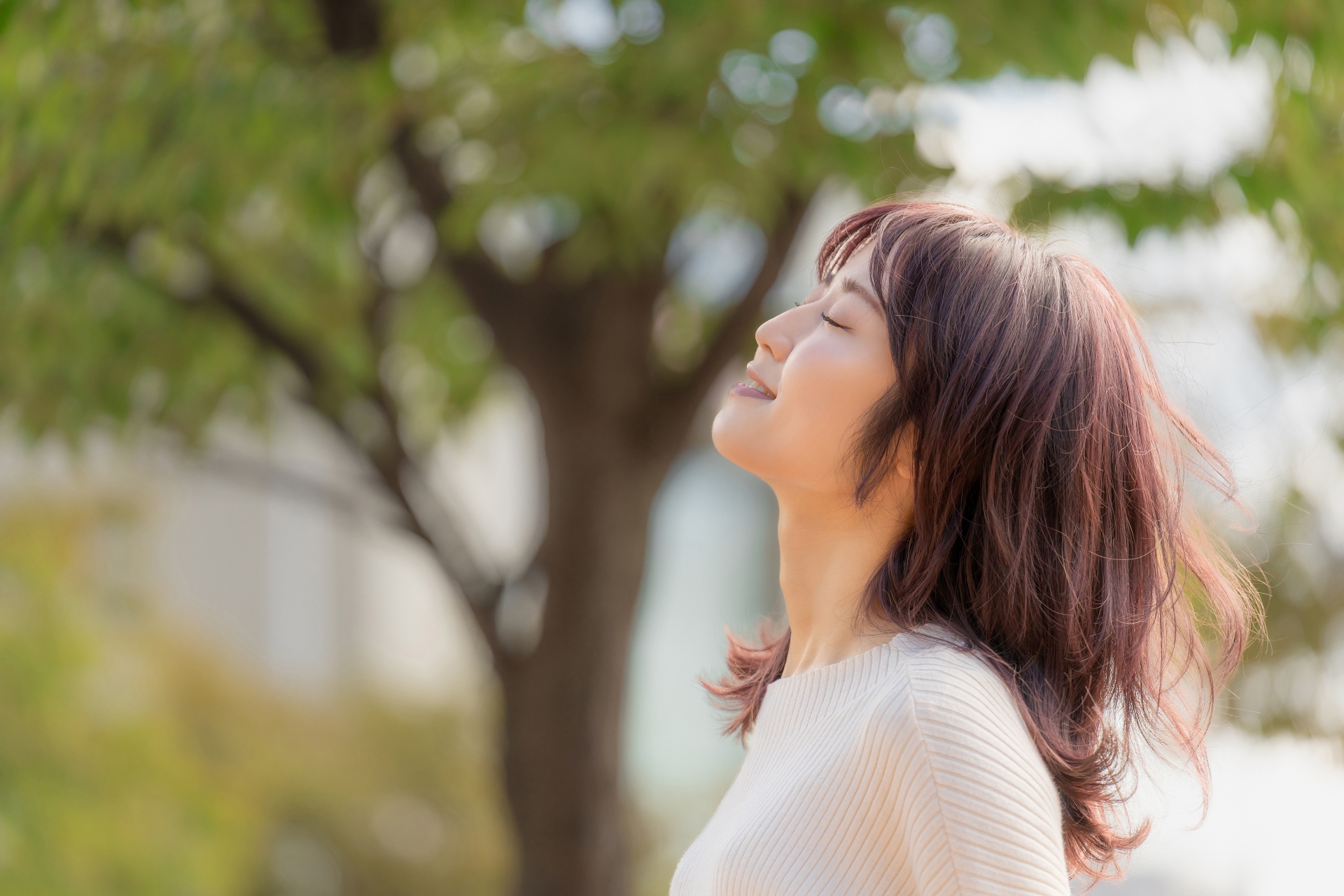 目を閉じて微笑みながら考える女性の横顔