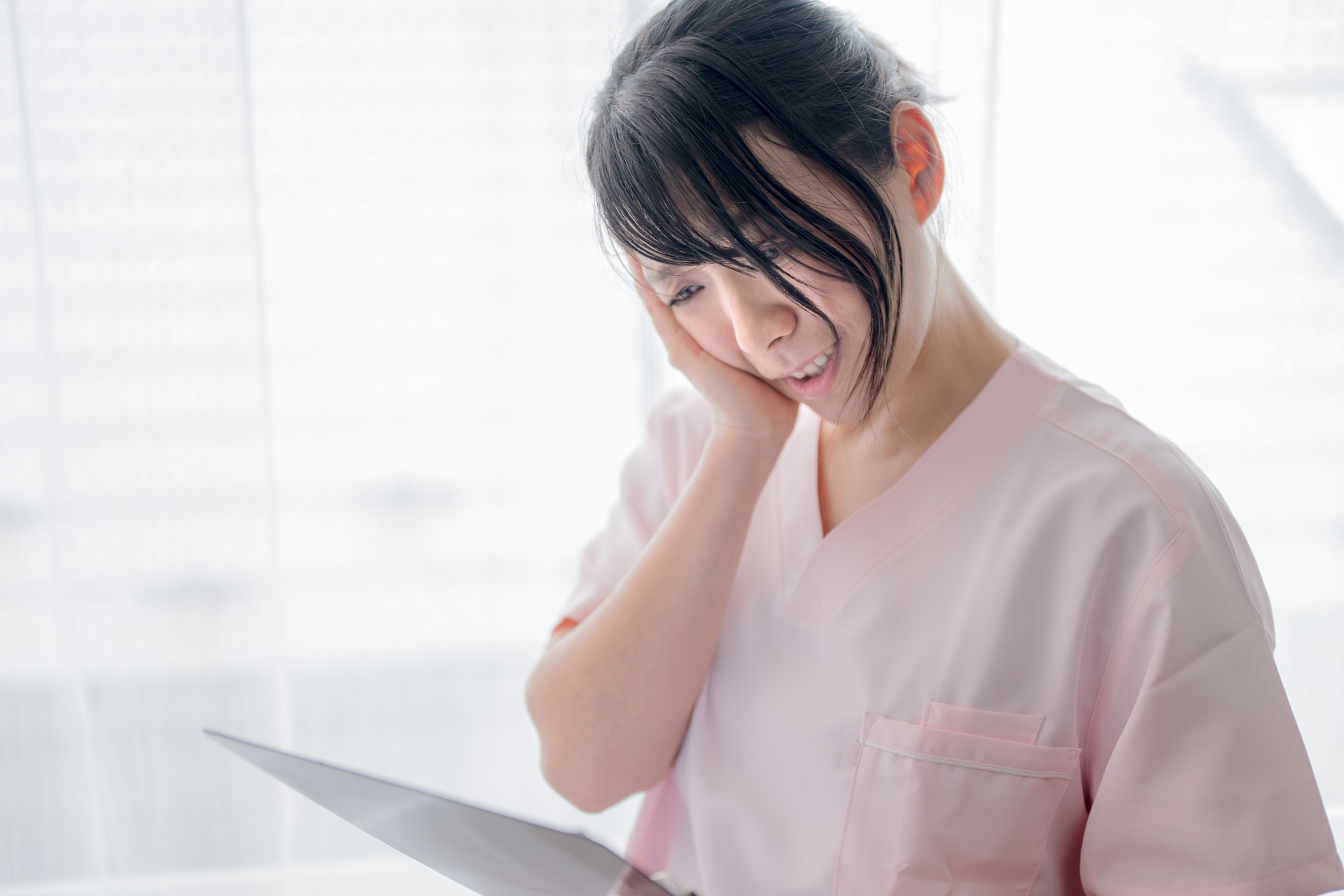 書類を見て頬に手を当てる介護士