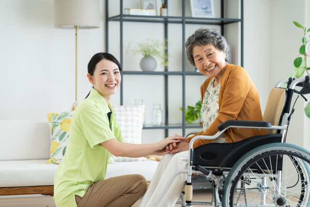 車椅子の女性の前に座る介護士