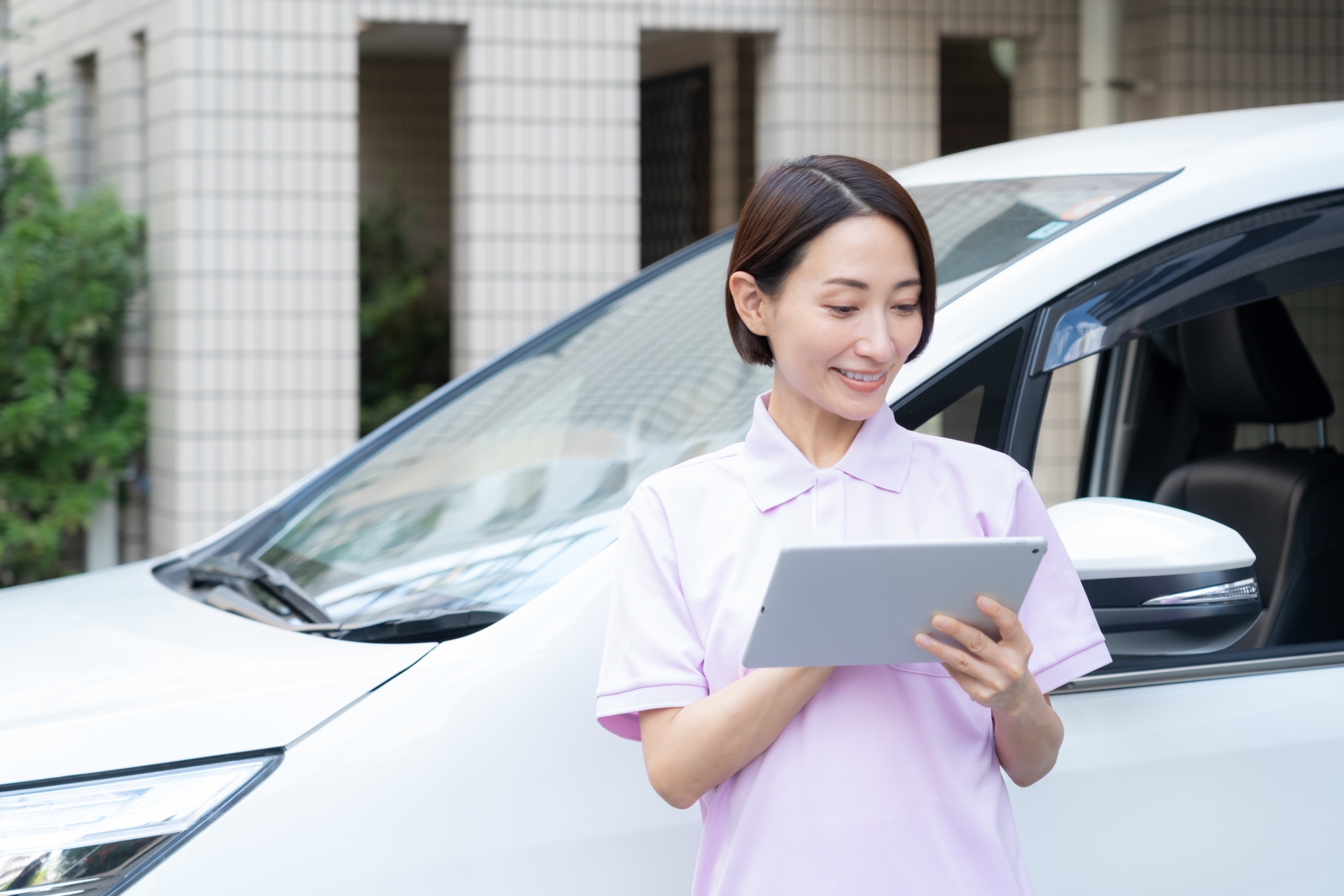 車のそばで書類を確認する女性