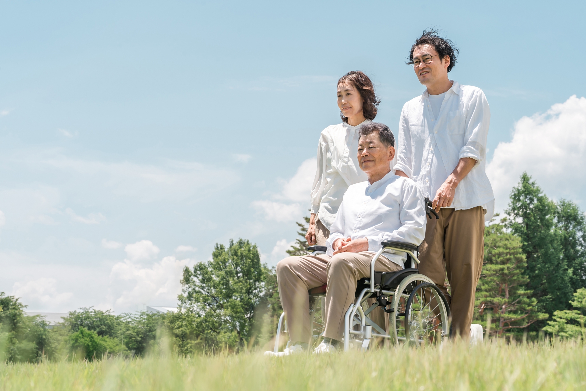 公園で散歩する介護士と車椅子のシニア男性