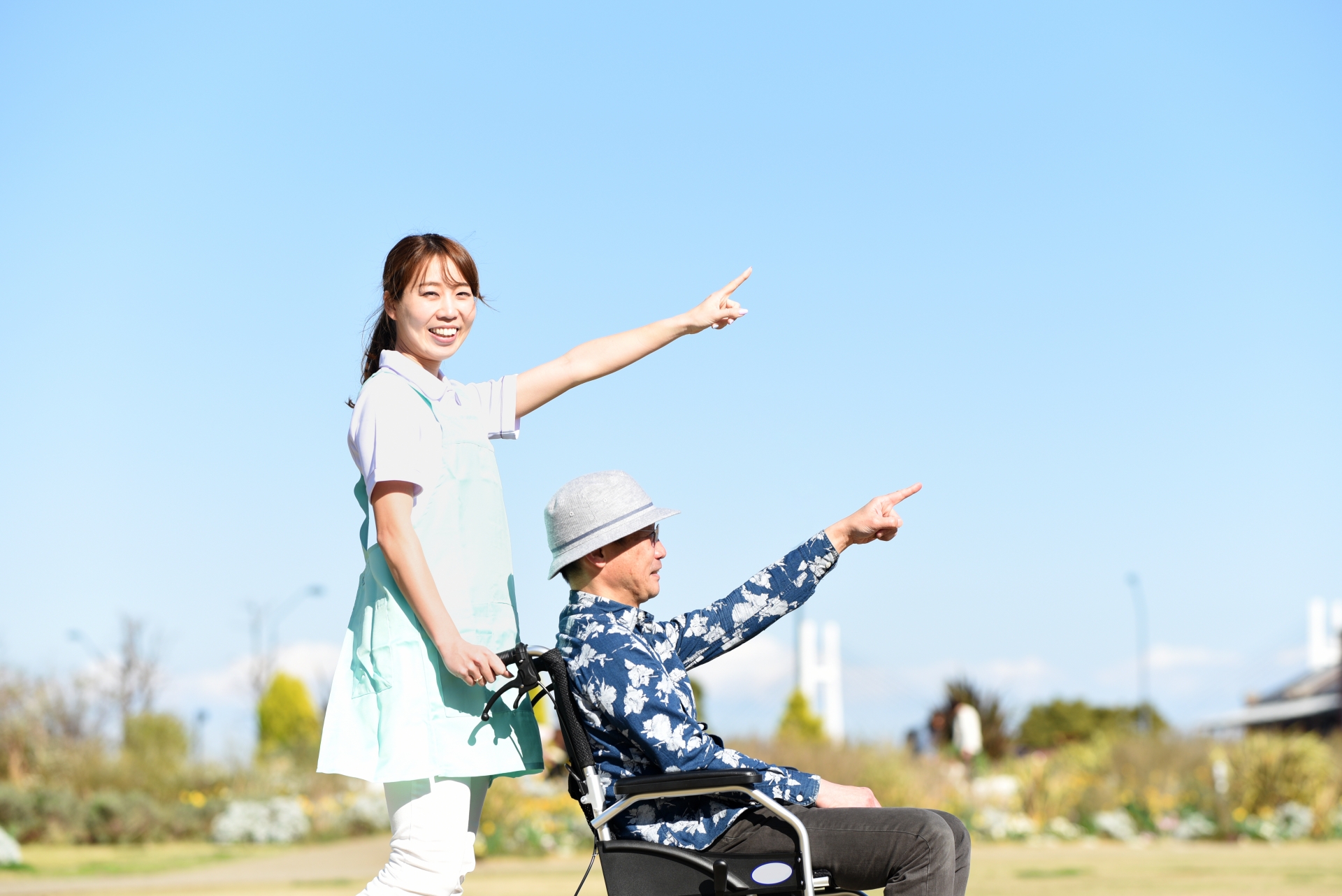 屋外にいる車椅子の男性と介護士