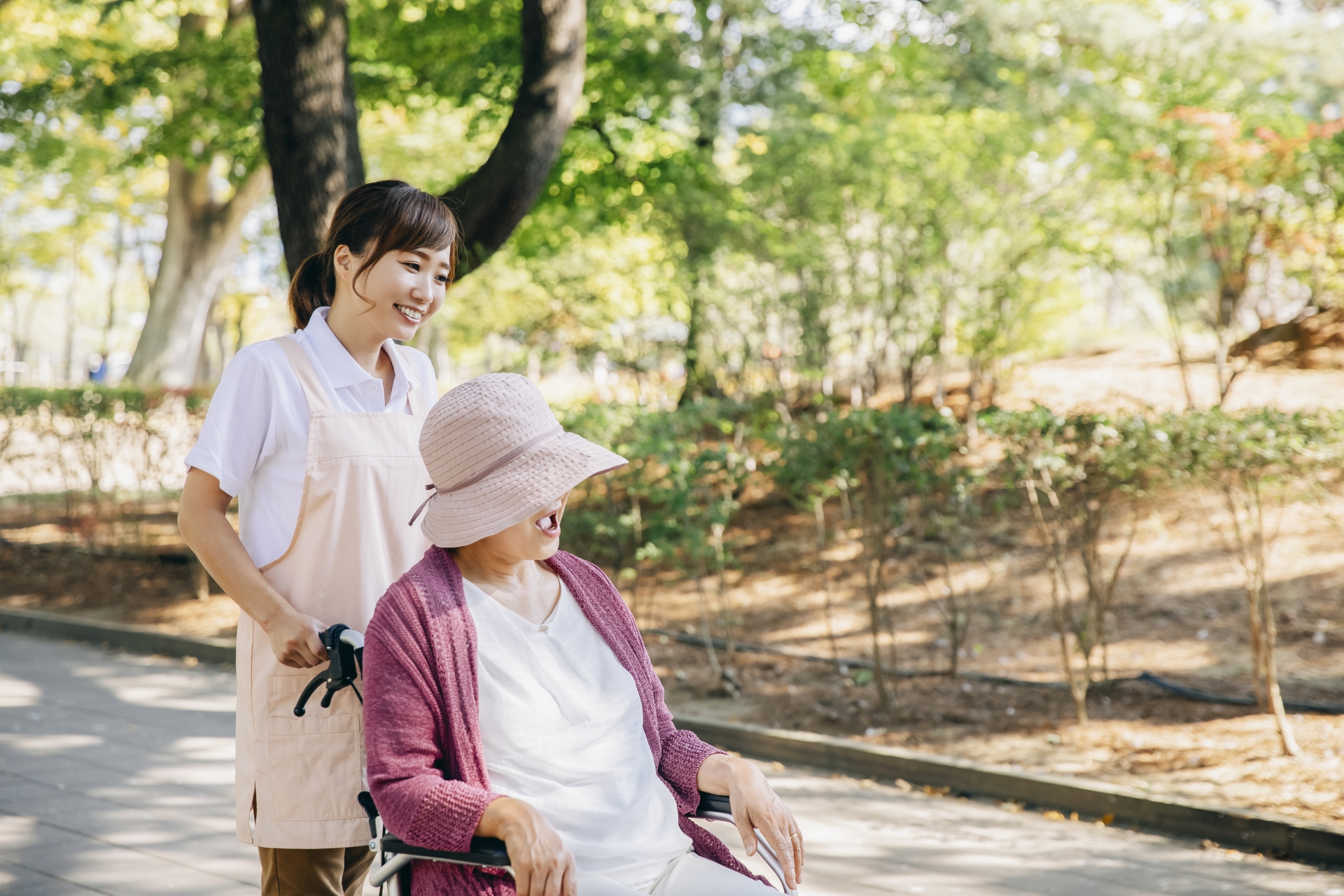 散歩する車椅子の女性と介護士