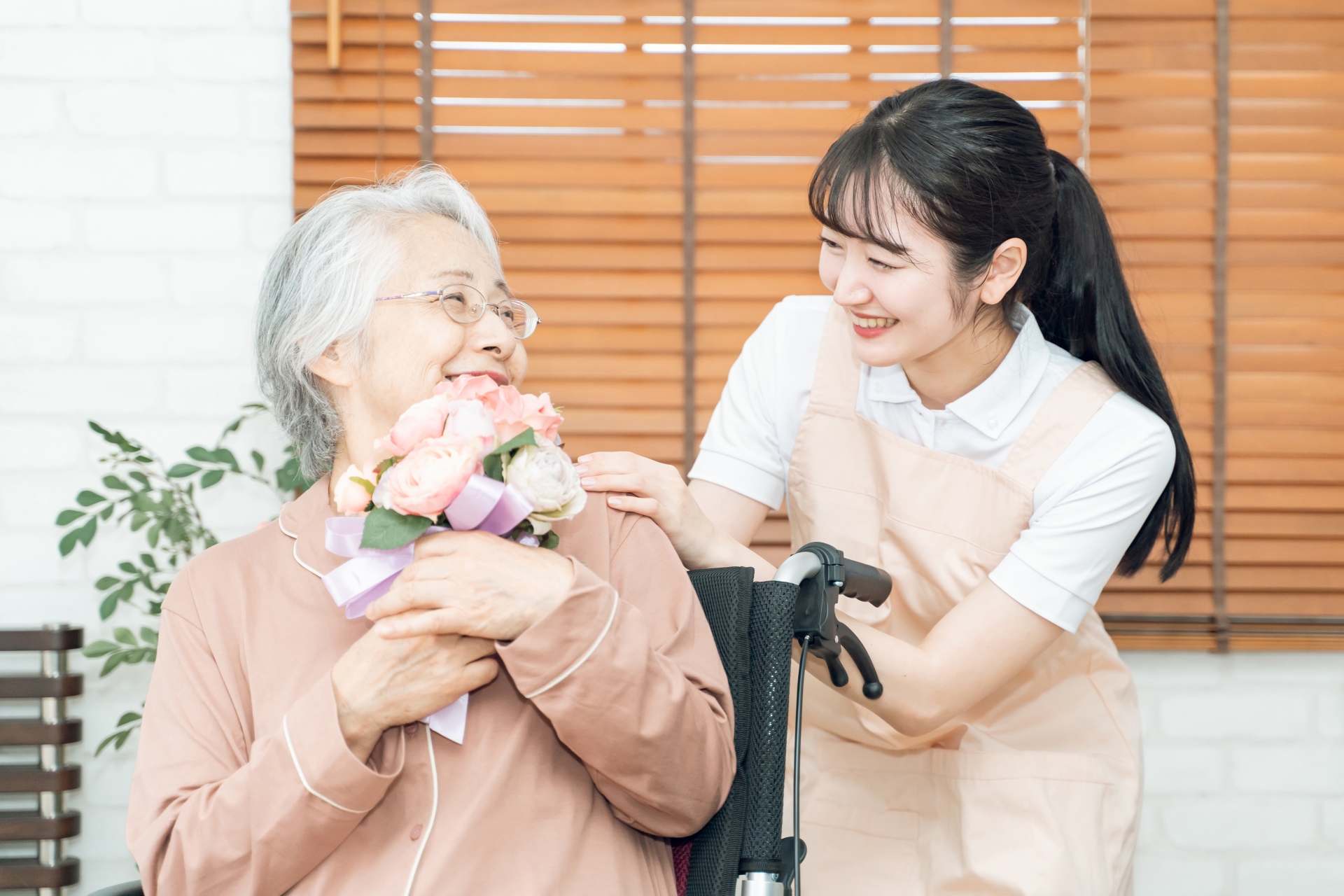 花束をもつシニアの女性と介護士