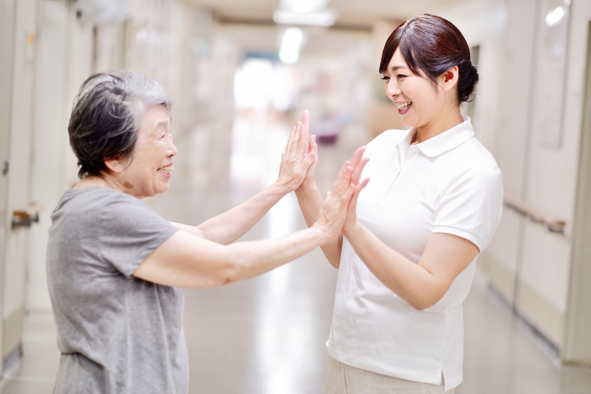 ハイタッチをする高齢者と介護士